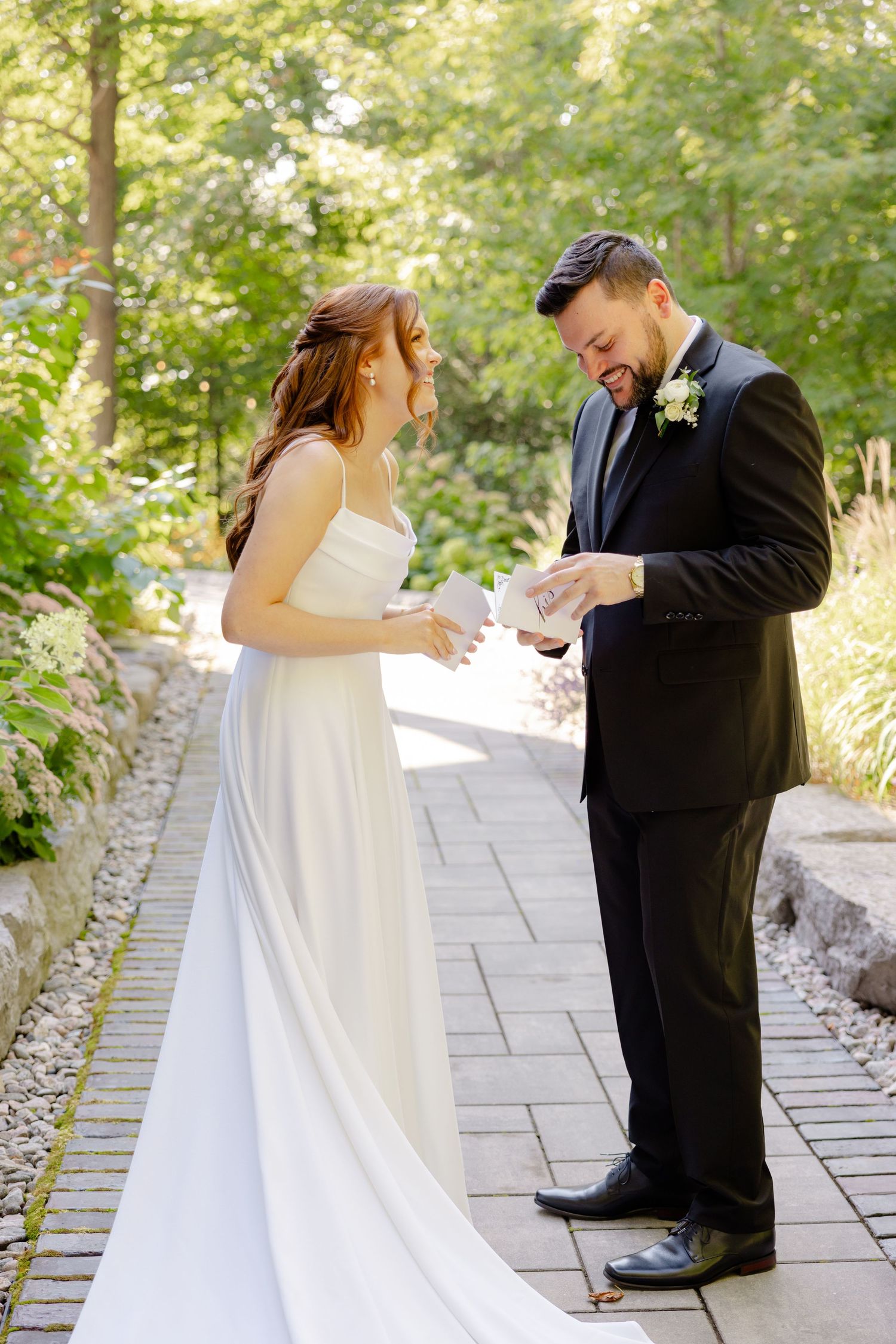 Joyful wedding moment shared on a garden path with sunlit trees in the background.