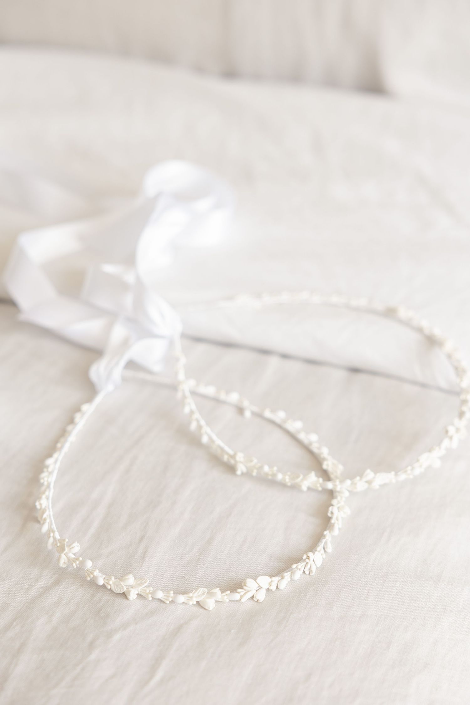 Delicate pearl-beaded bridal crown displayed on white fabric.