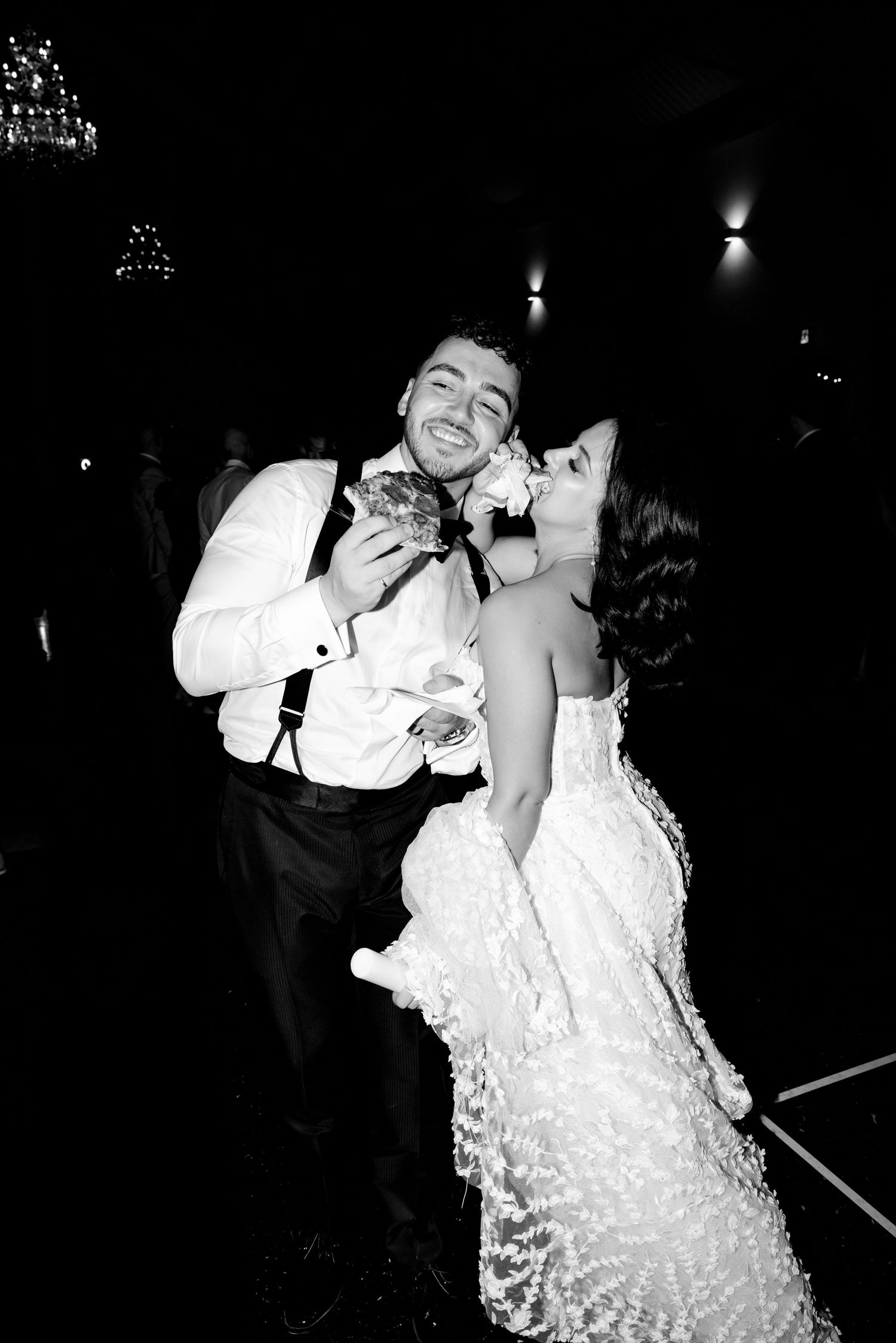 A joyful black and white moment showing a couple in formal attire laughing during their wedding reception.