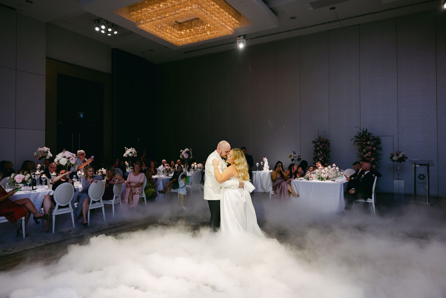 Romantic first dance of newlyweds surrounded by dry ice fog in an elegant ballroom.