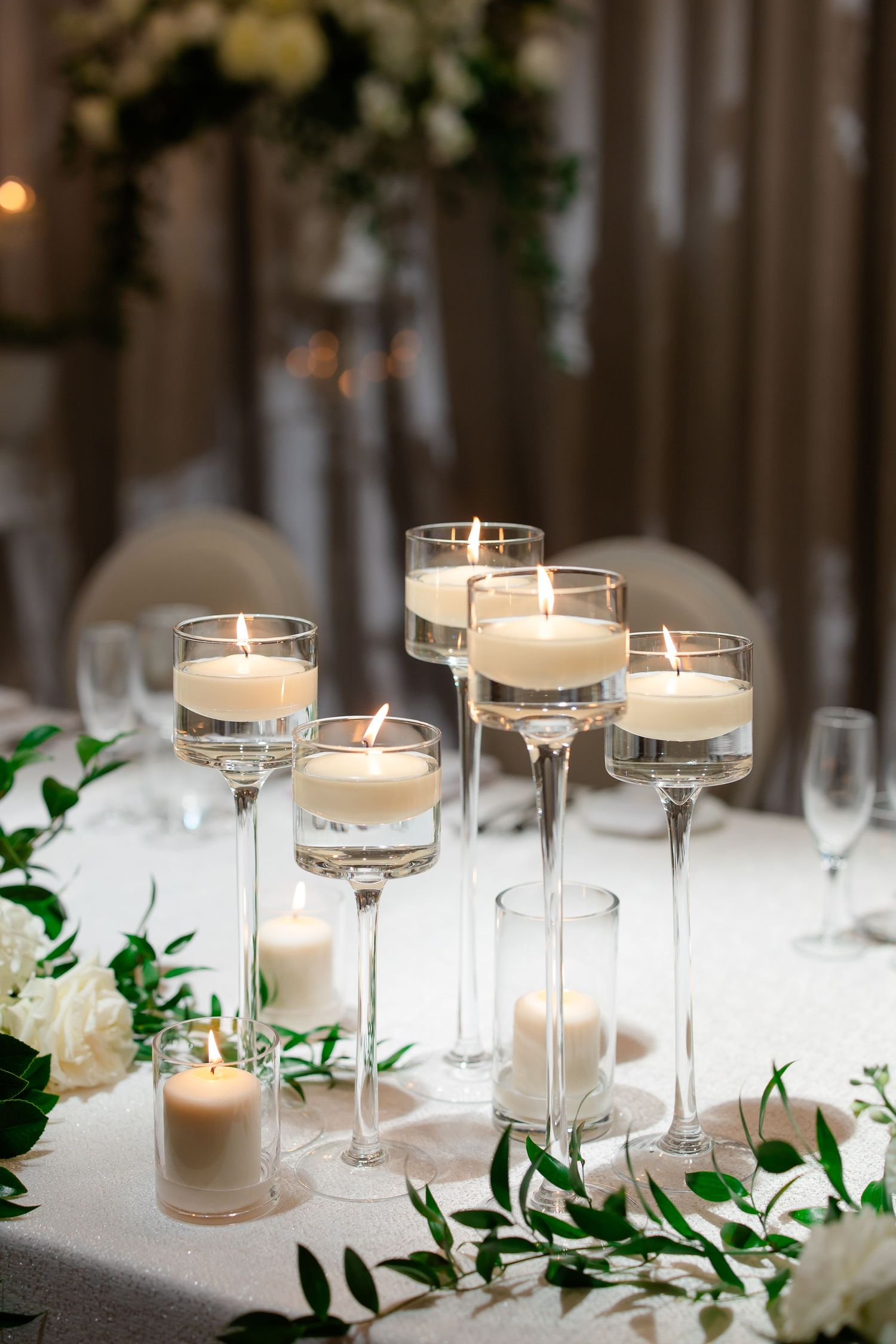 Elegant wedding table decor with floating candles and white floral arrangements.