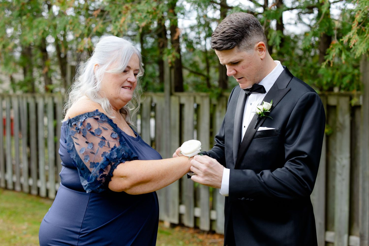 Two people share an intimate moment during a formal event in an outdoor setting.