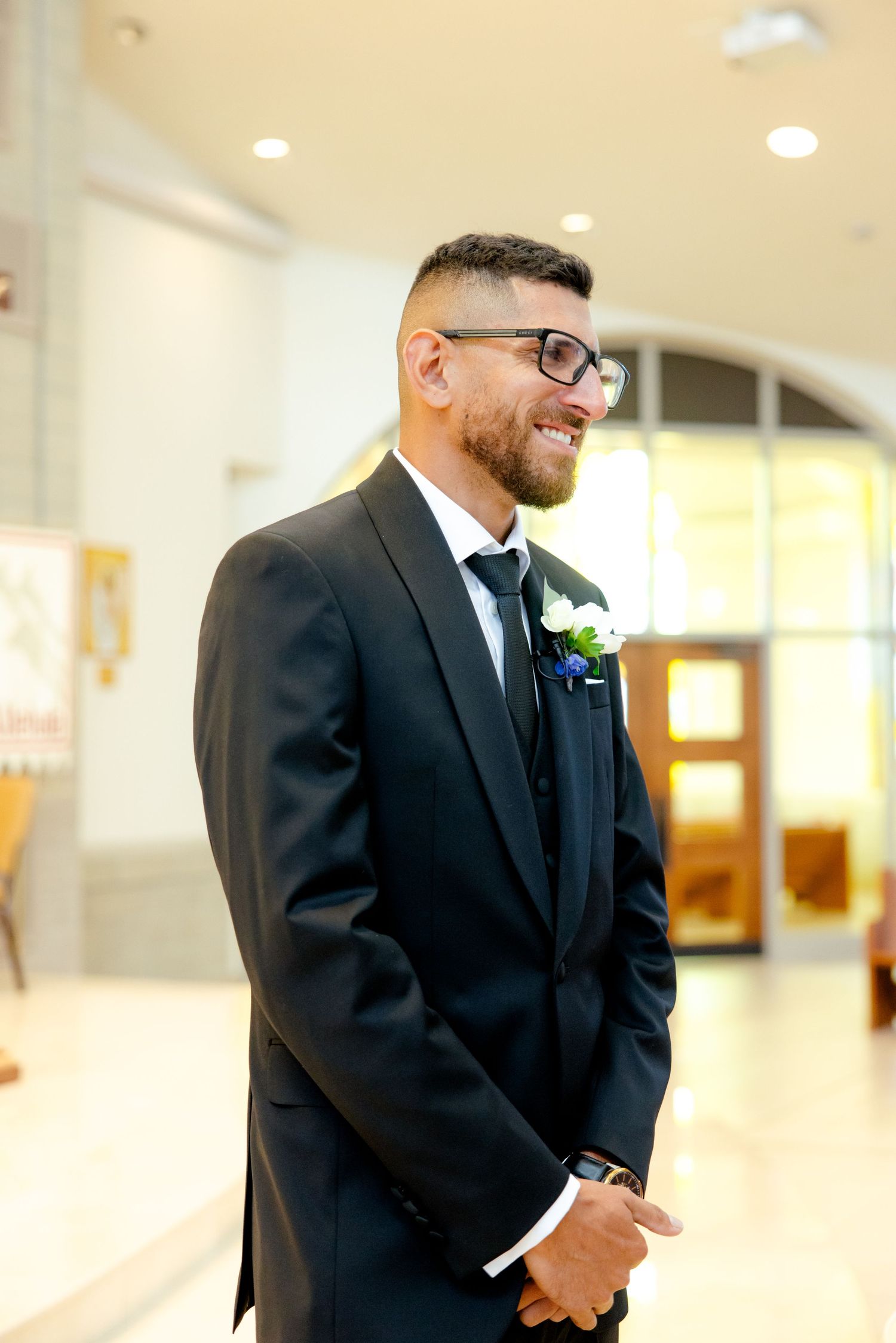 A formal wedding portrait in an indoor church setting with natural lighting.