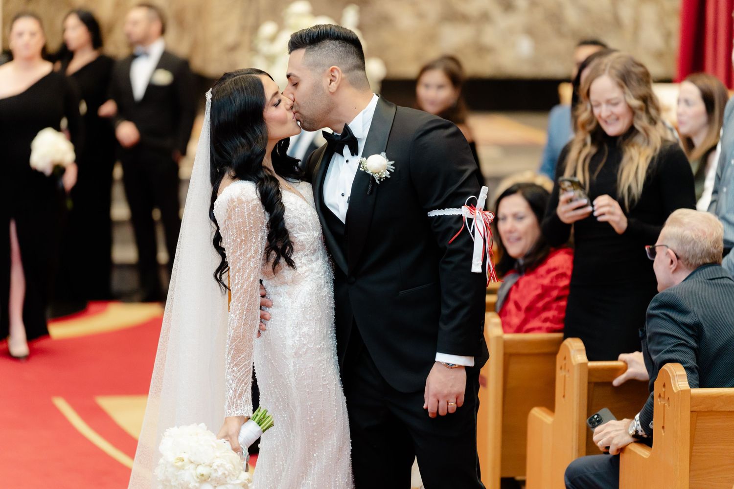 A couple shares an intimate moment during their wedding ceremony in a church with red carpet.