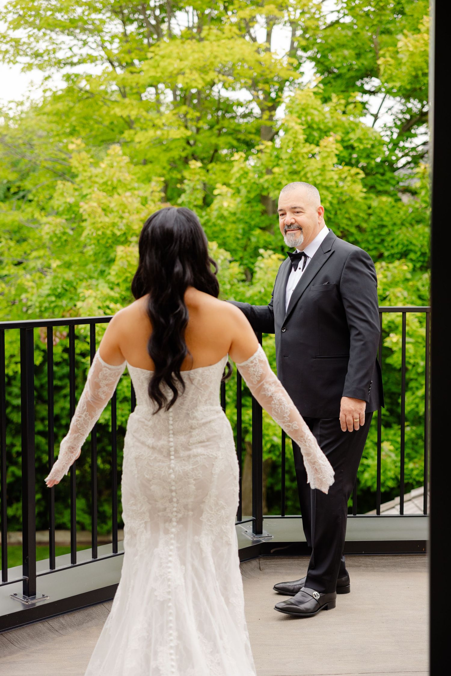 First look wedding photo sequence shows a bride and groom seeing each other on an outdoor deck surrounded by greenery.