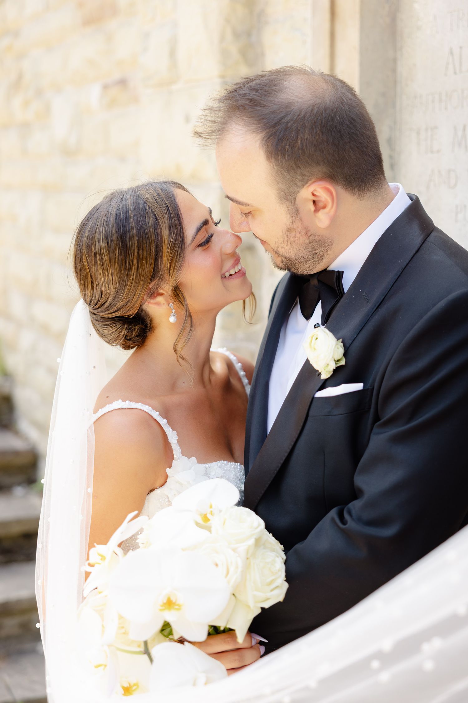 A romantic wedding moment with a couple embracing while the bride holds a white bouquet during their special day.