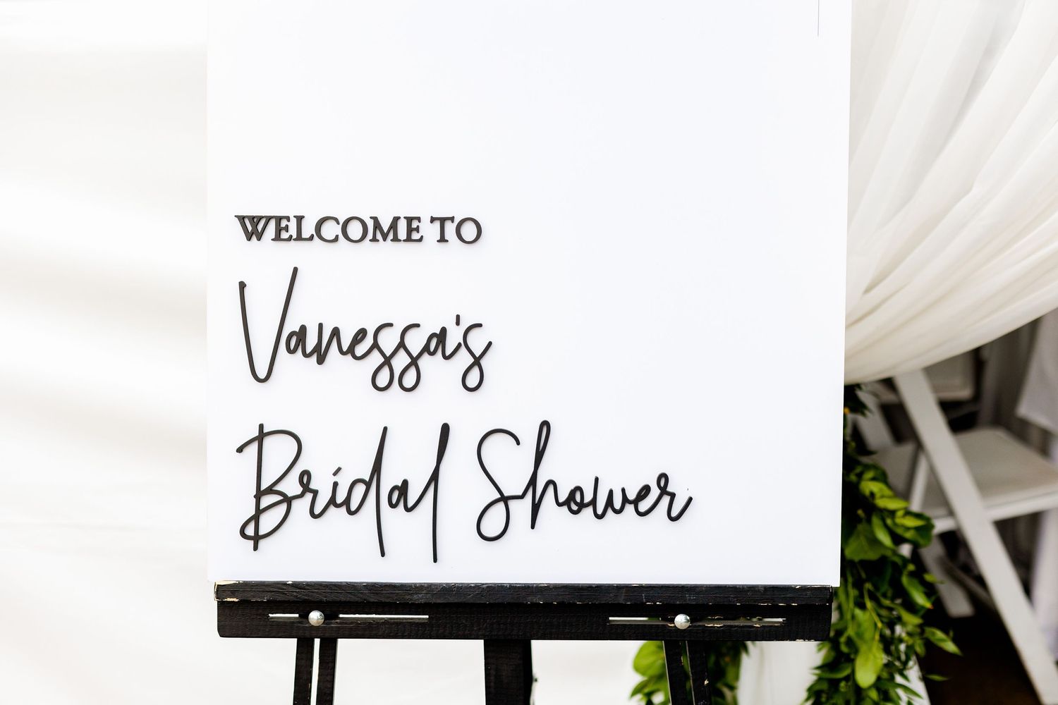 Black and white welcome sign for Vanessa's bridal shower on an easel stand.