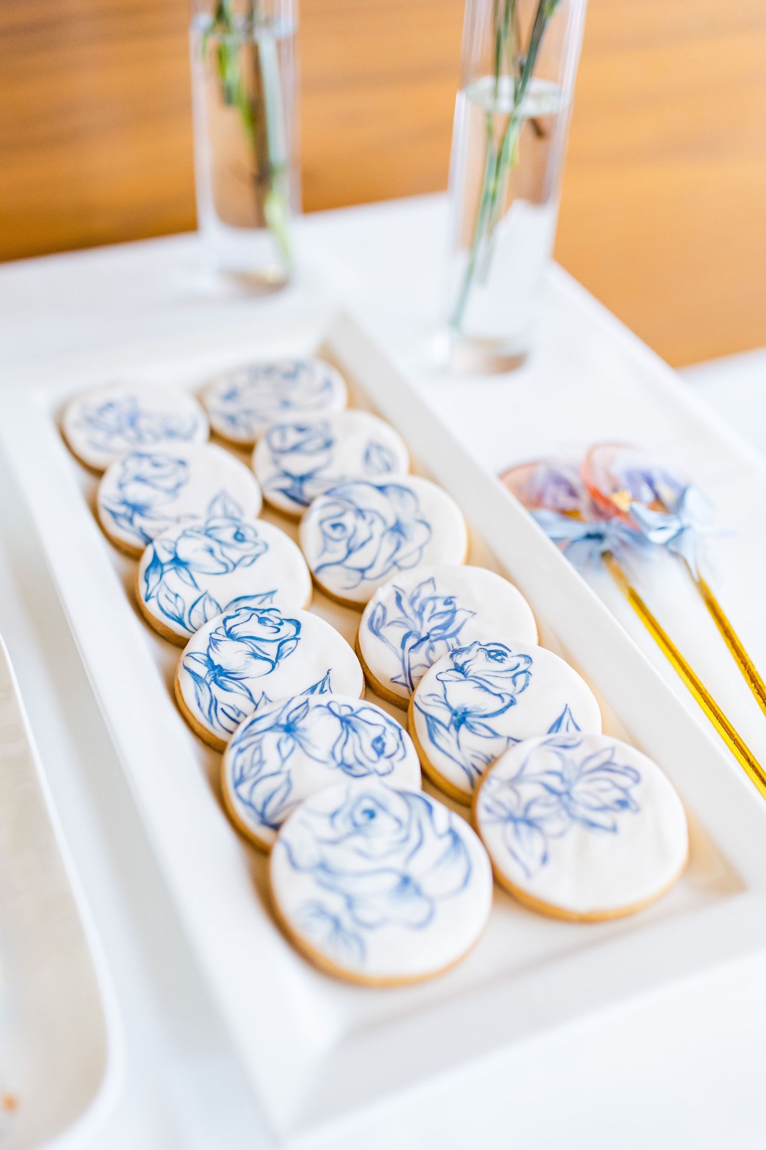 White cookies decorated with delicate blue floral designs arranged on serving platter.