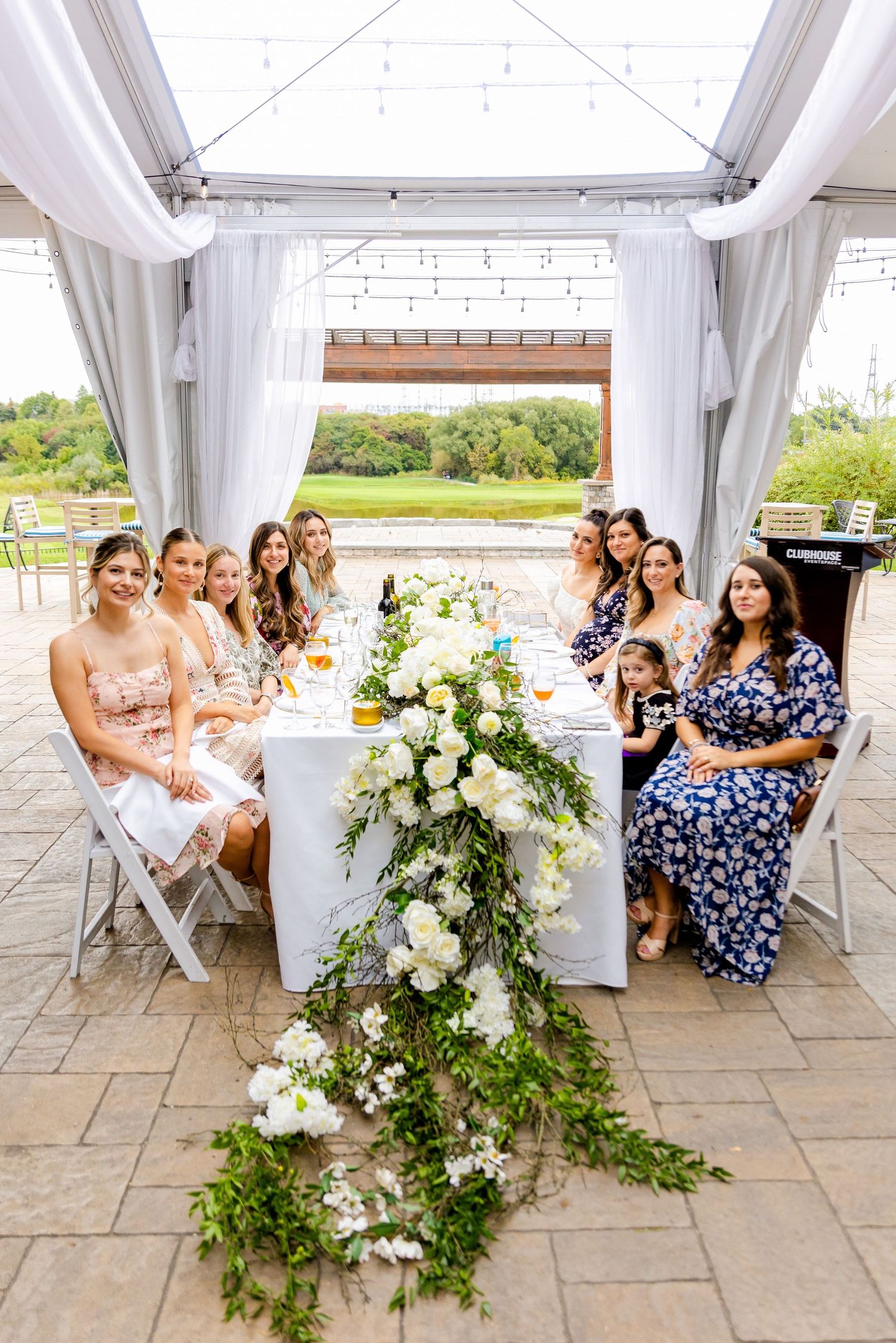 Elegant table setting with cascading white floral centerpiece under a draped white tent.