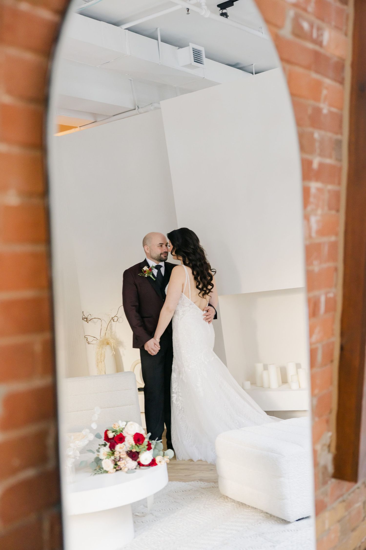 A wedding portrait framed through an archway with exposed brick details.