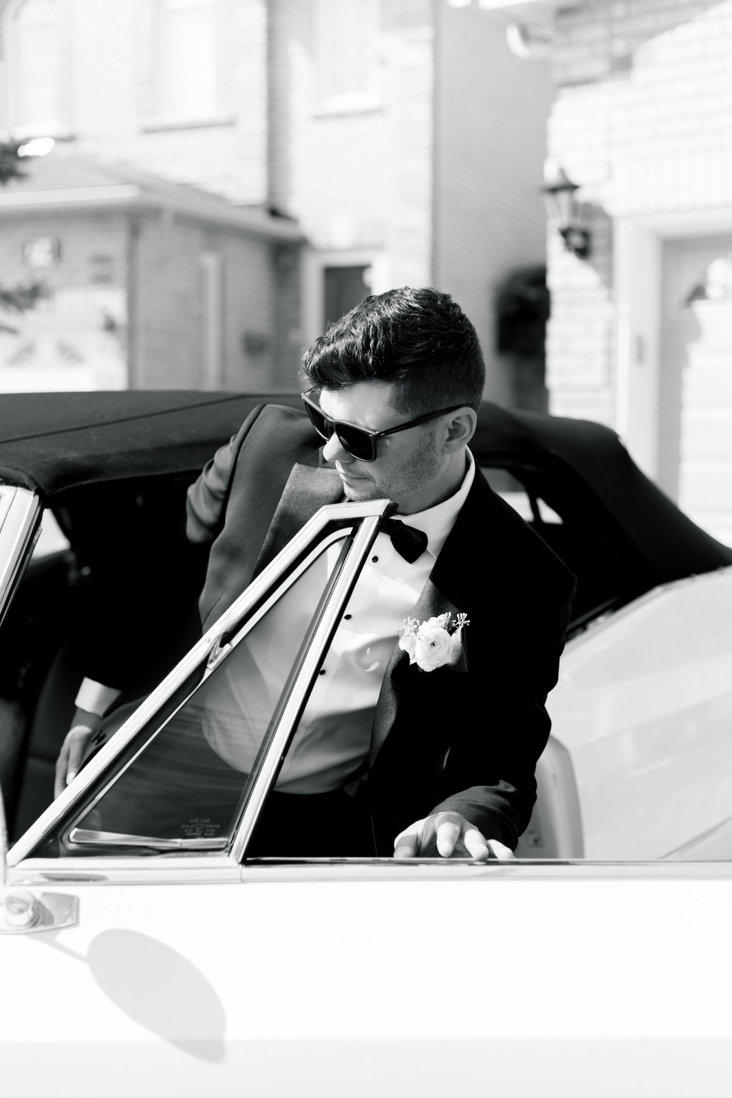 Black and white photo of someone wearing sunglasses in vintage car.