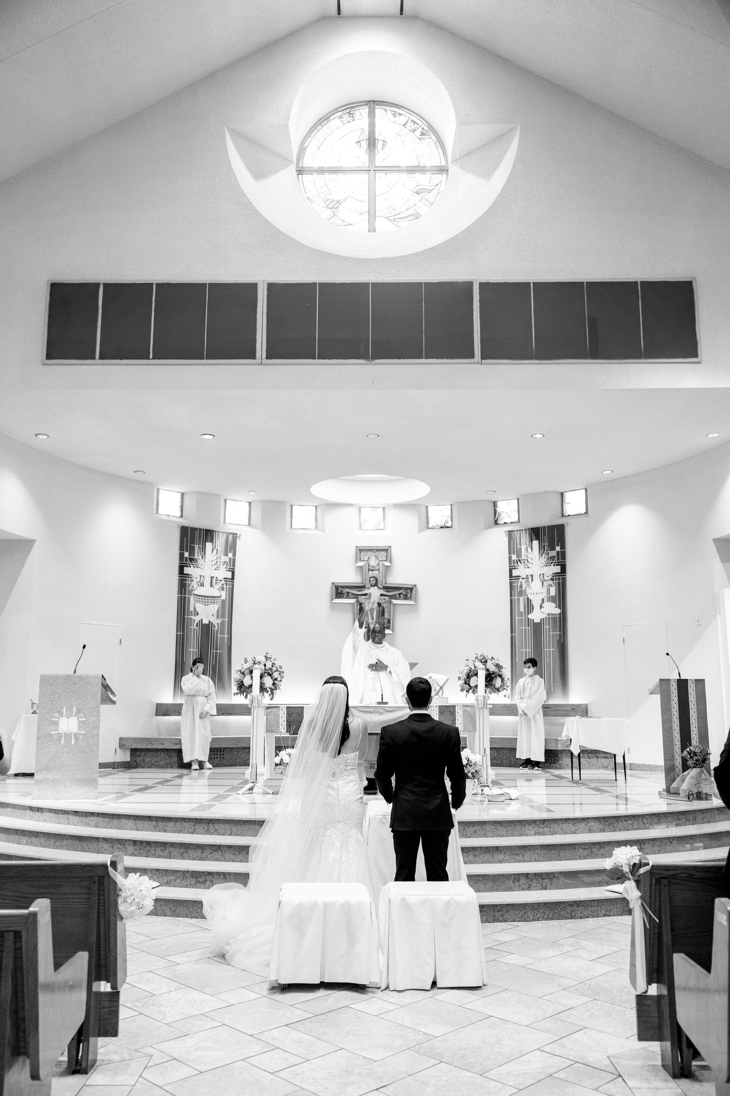 A black and white photo of a couple standing at the church altar during their wedding ceremony.
