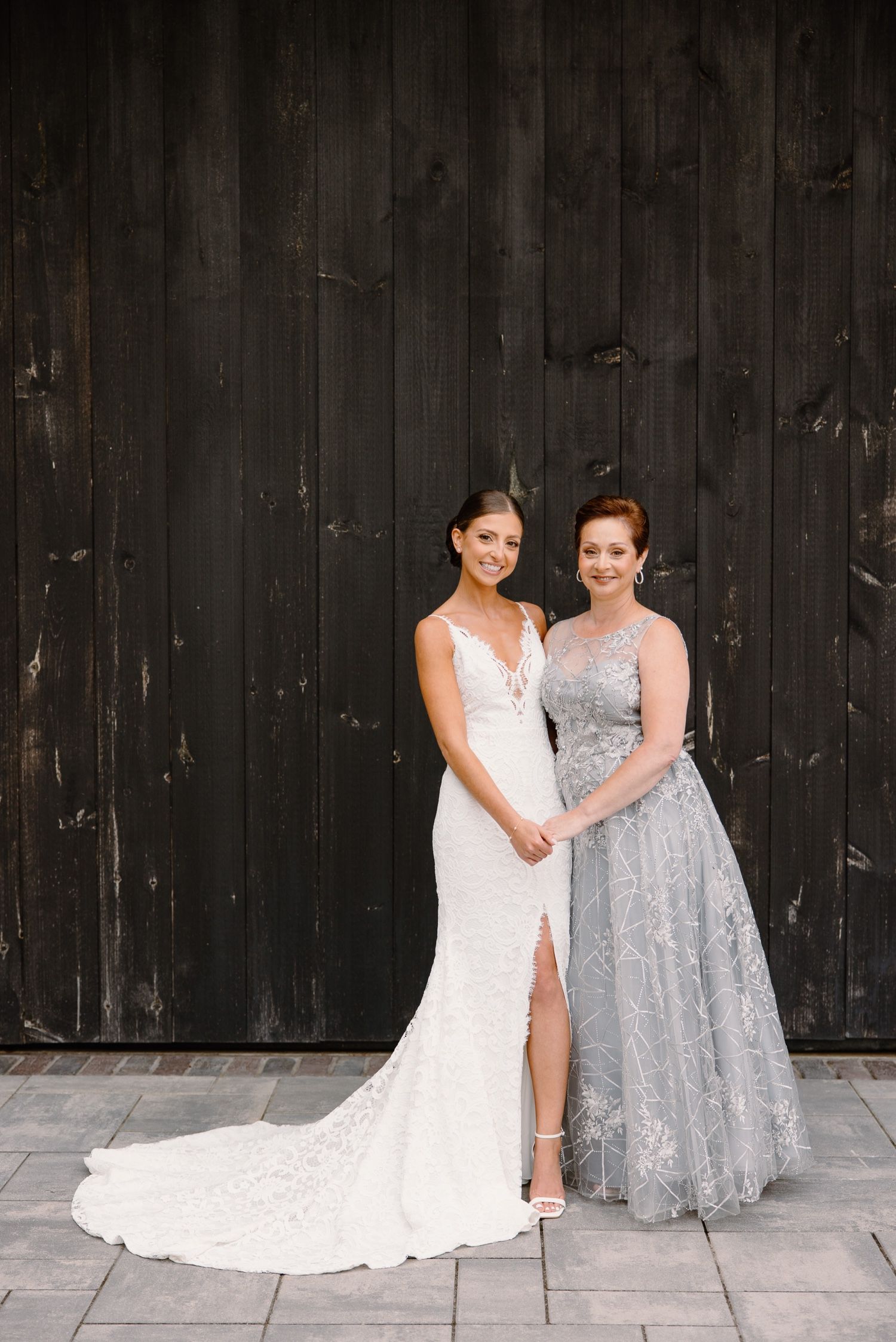 Wedding portrait against dark wooden wall featuring formal attire.
