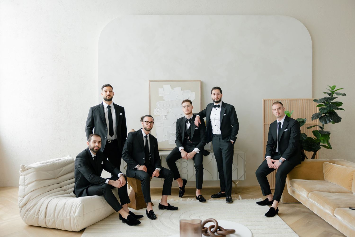 Groomsmen relaxing on modern furniture in contemporary white room setting.