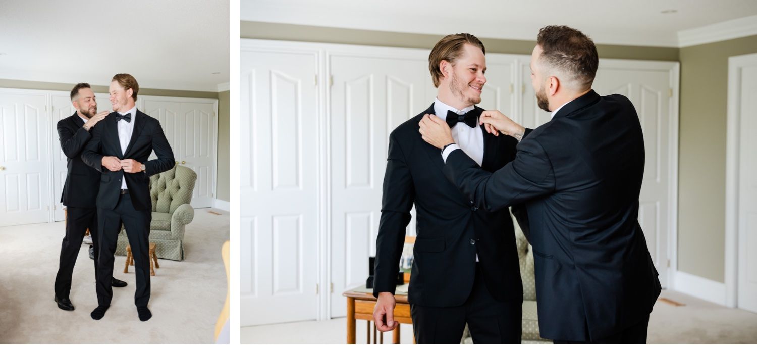 Two people in formal black suits adjusting each other's bowties and helping with wedding preparations.