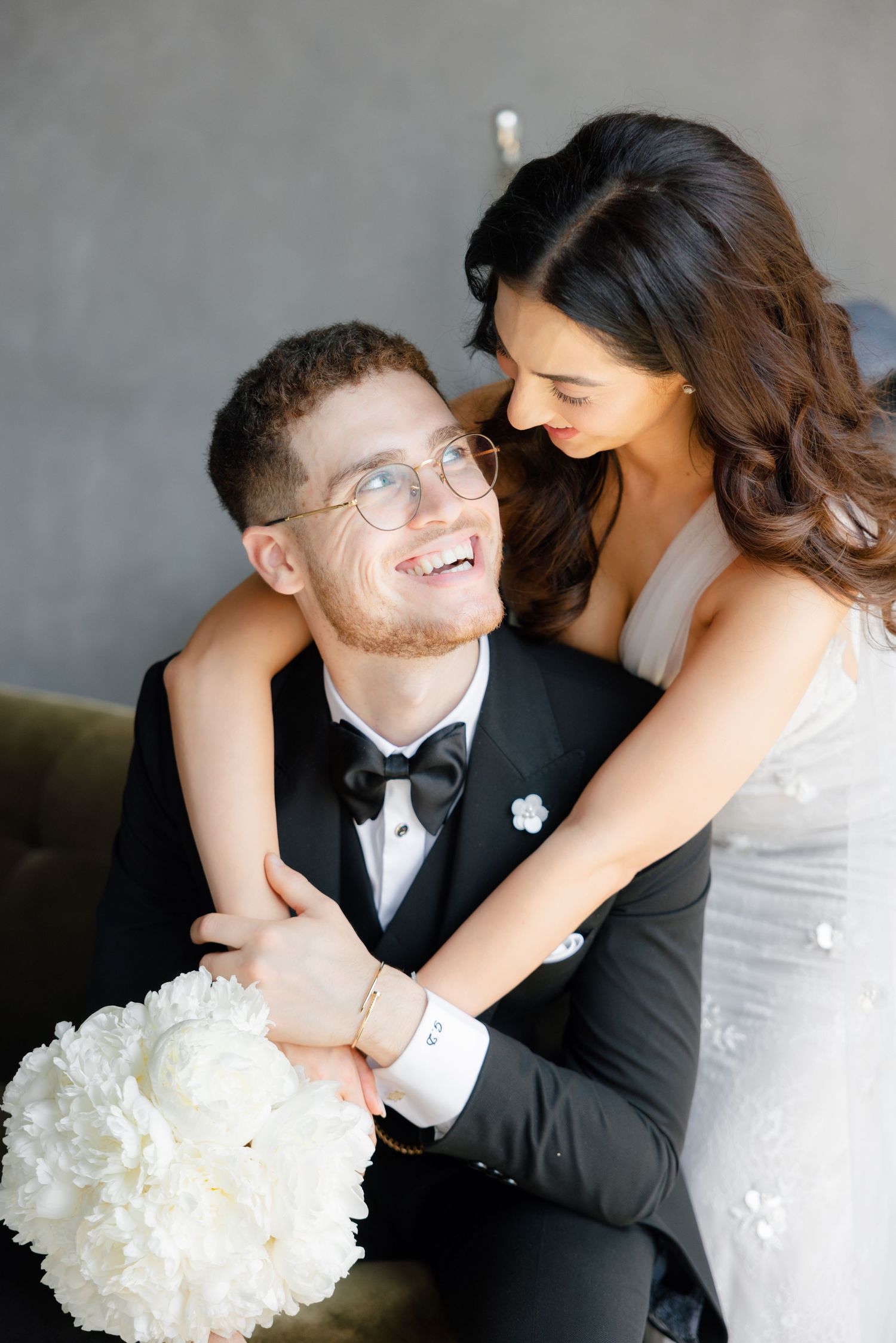 A tender wedding moment between newlyweds with a white bouquet and formal attire.