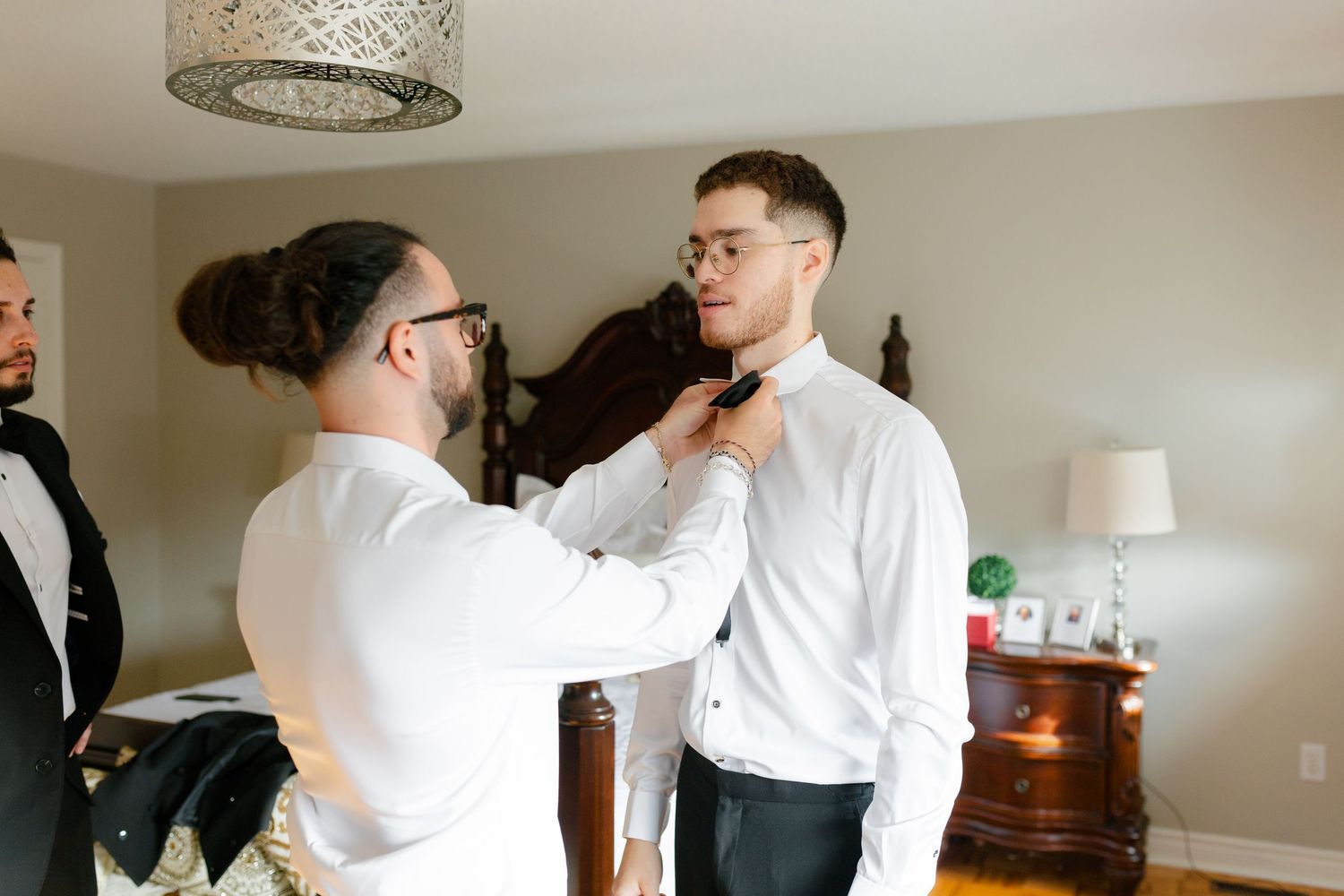 Someone helping adjust another person's bowtie before a formal event.