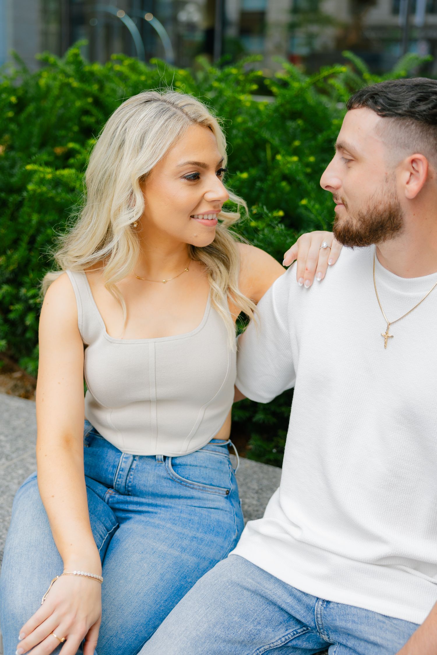 Couple shares intimate moment while sitting outside contemporary office building.