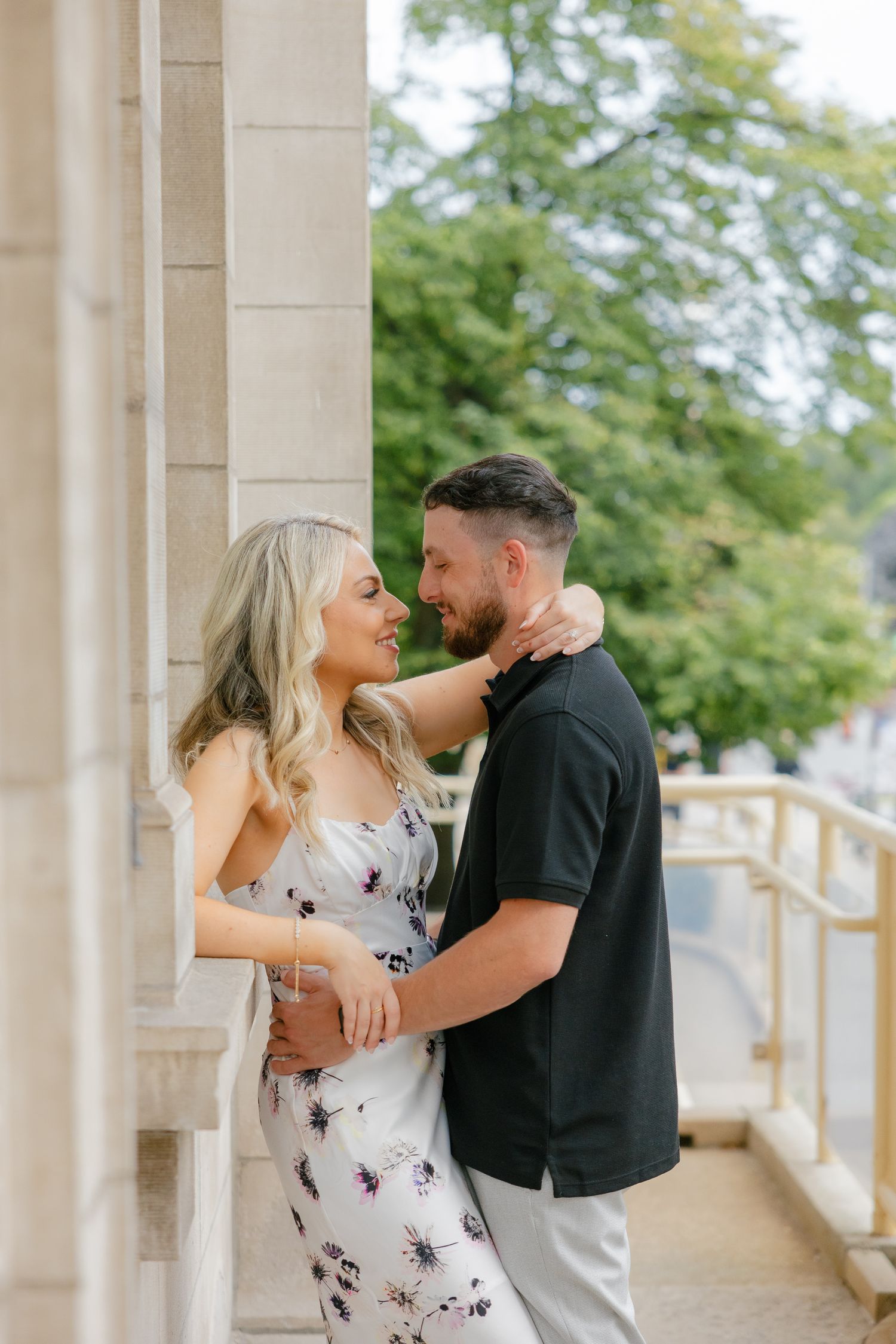 A romantic embrace captured between stone pillars on an elegant veranda.