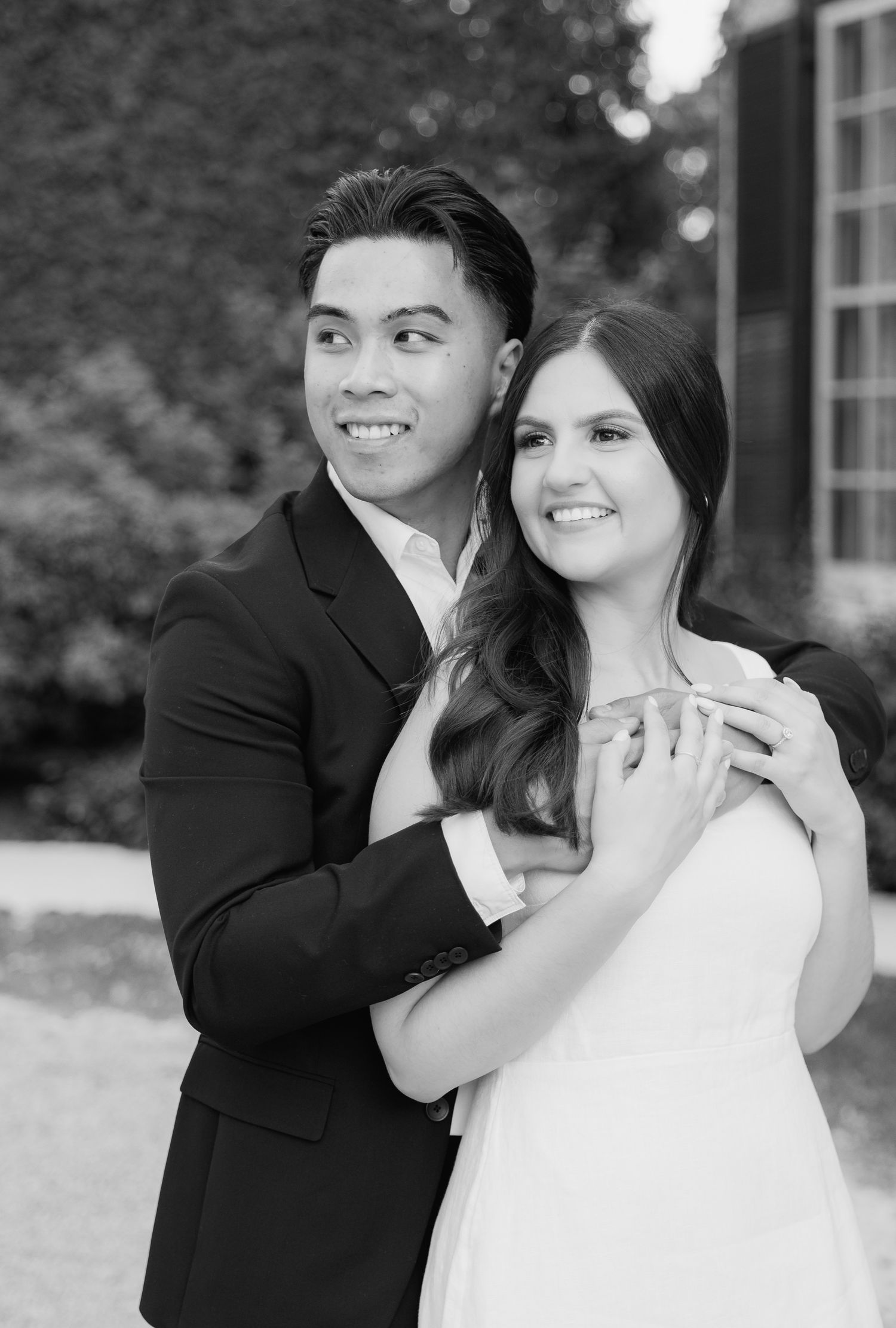 Black and white portrait of couple in formal attire showing engagement ring.