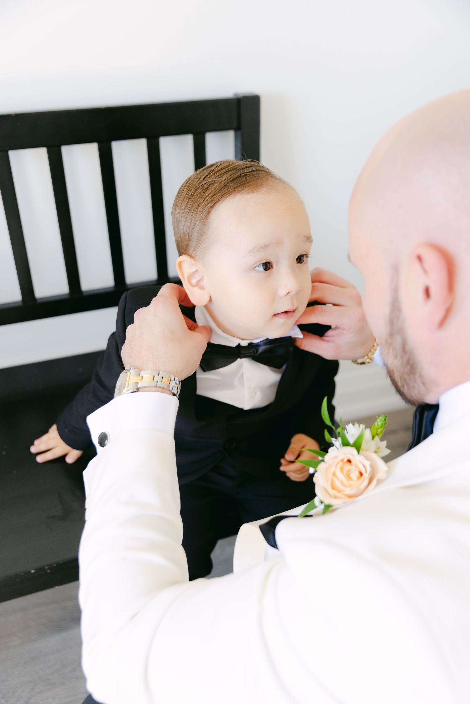 A sweet moment of adjusting a tiny bow tie on a formal black tuxedo.