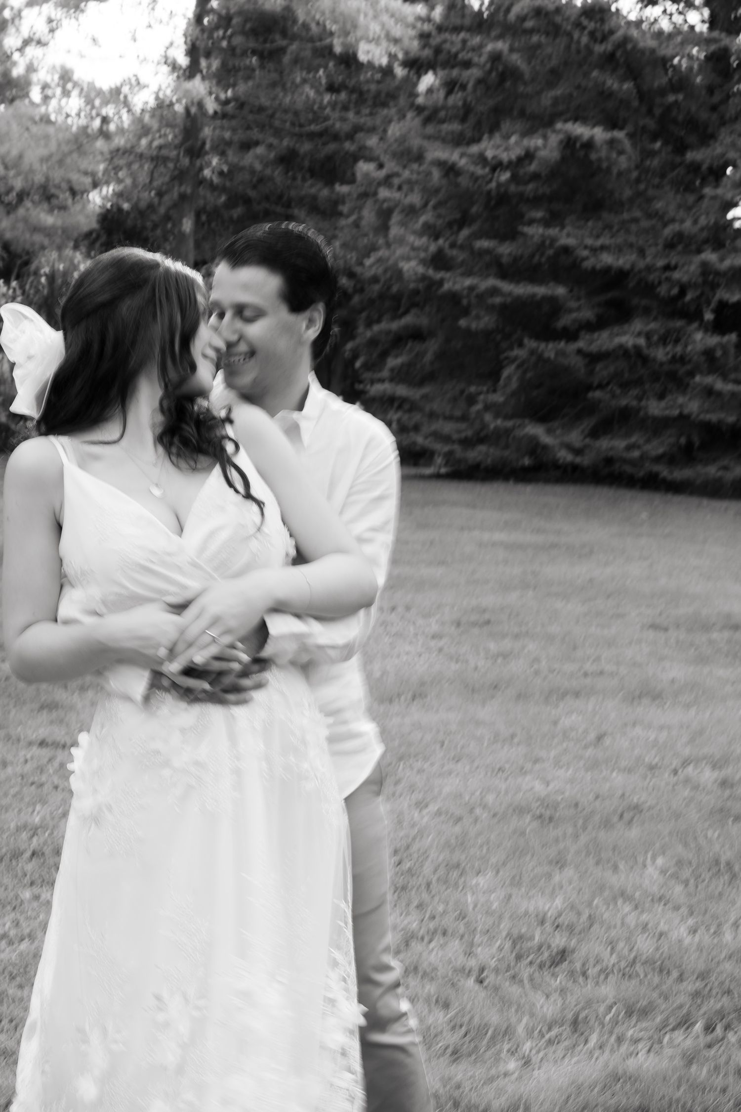 Black and white candid photo of couple dancing and embracing outdoors.