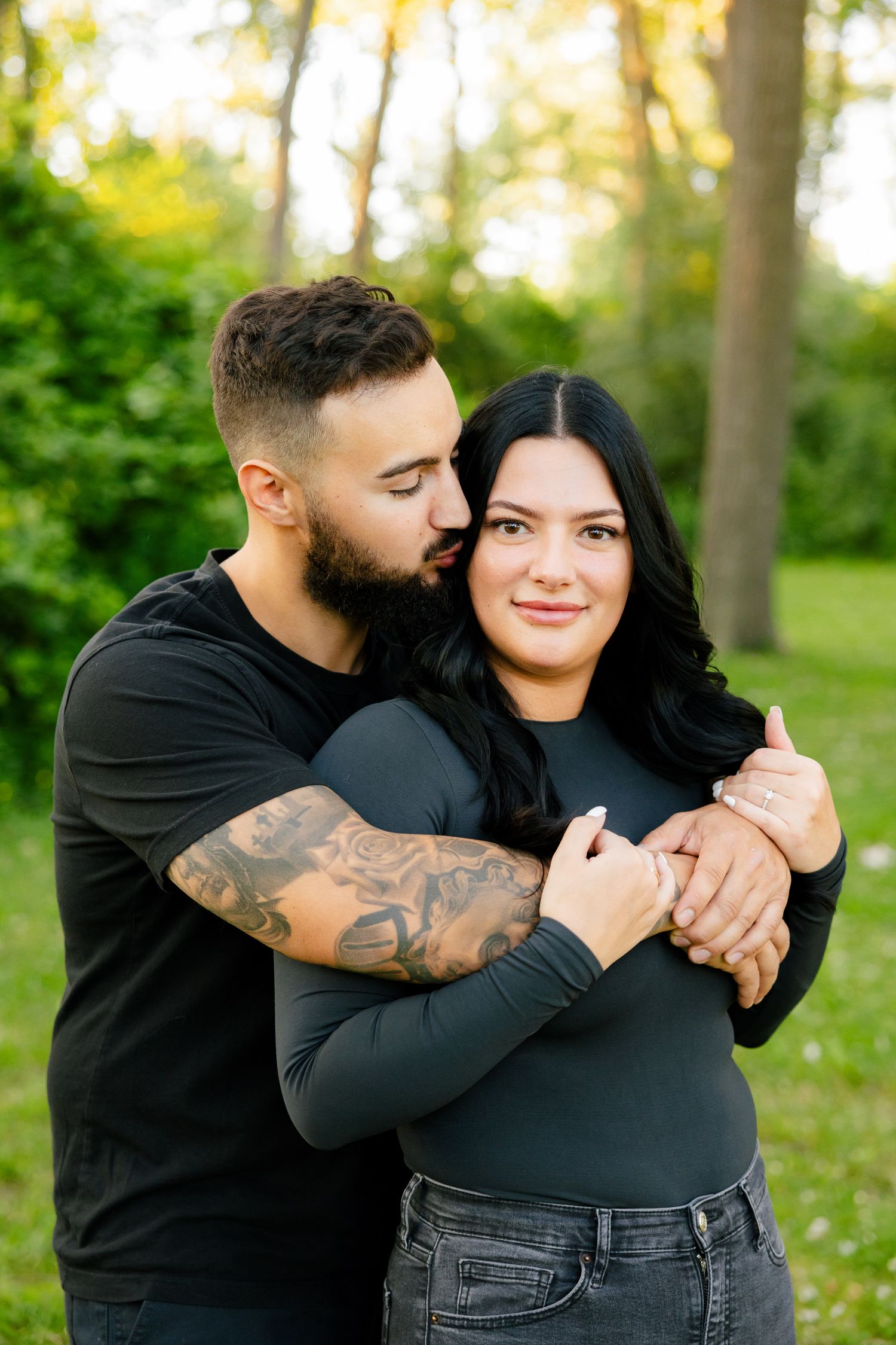 Sweet candid moment between couple embracing in sunlit outdoor garden setting.