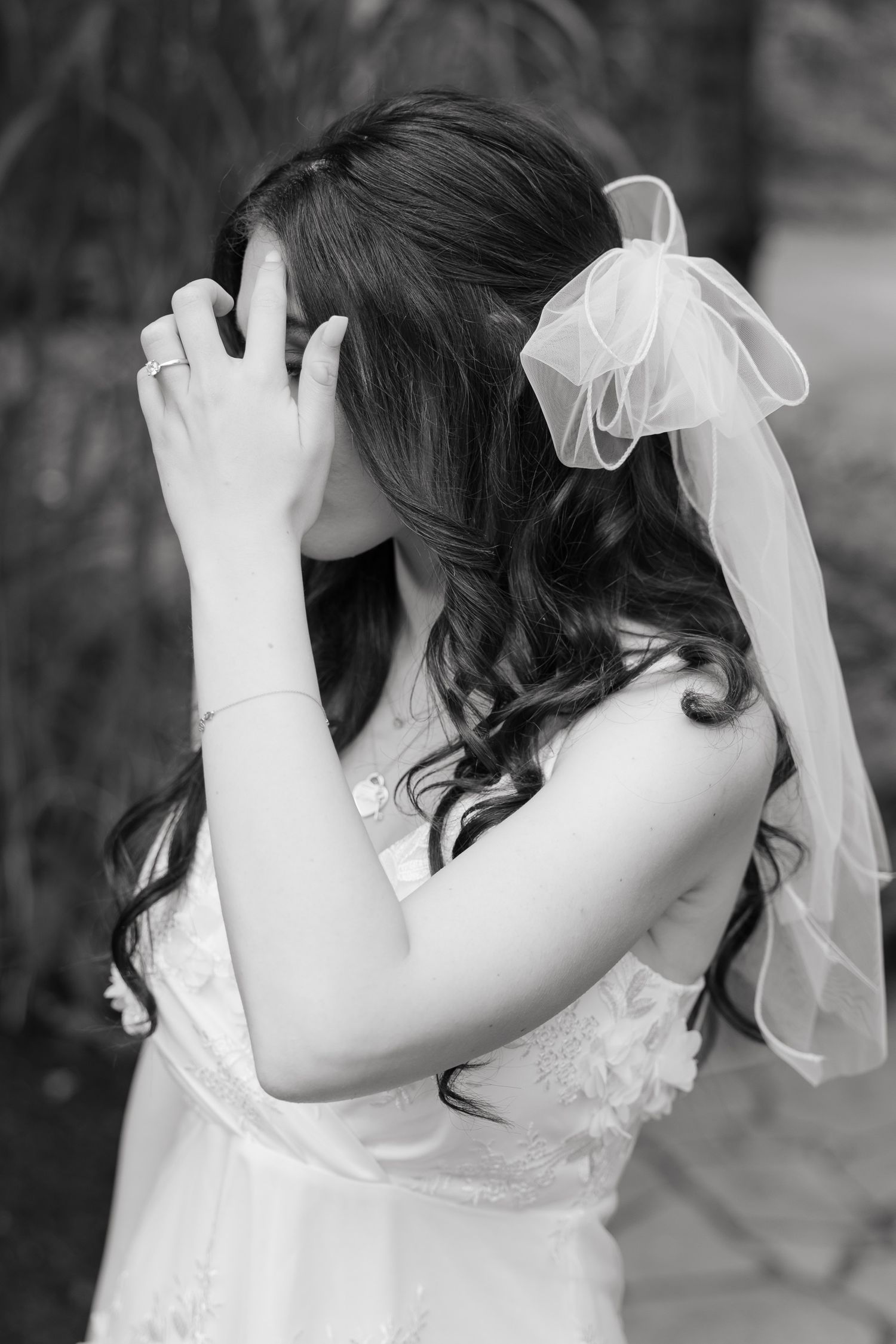 Artistic black and white portrait of bride with flowing veil and curled hair.