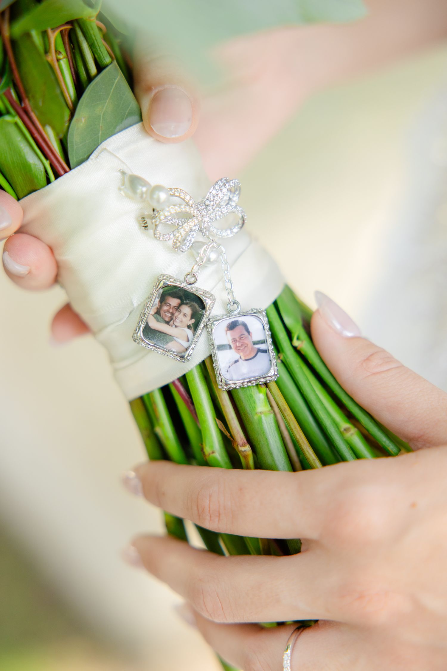 Memorial photo charms and a decorative butterfly attached to a green floral bouquet stem.