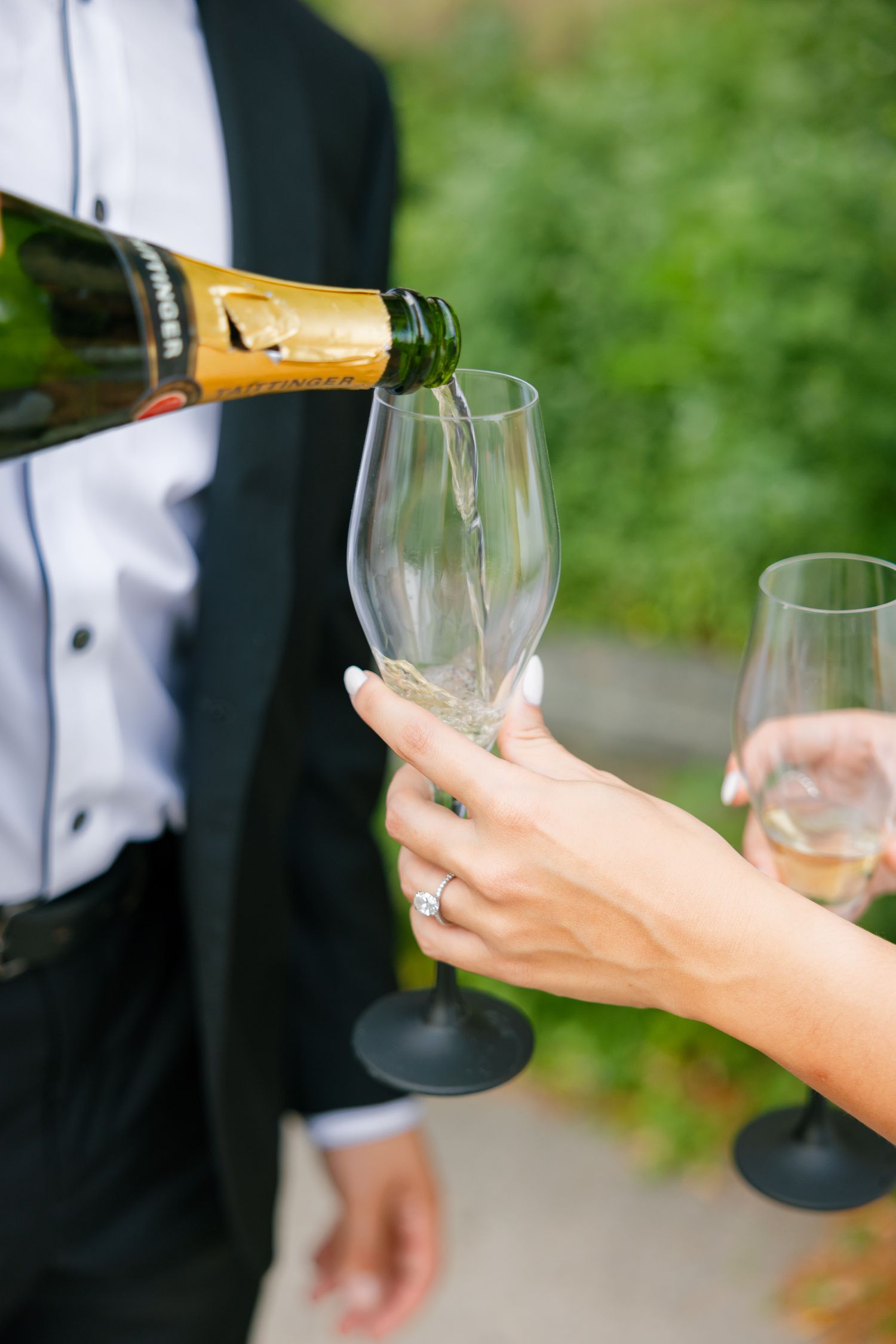Champagne being poured into elegant wine glasses during an outdoor celebration.