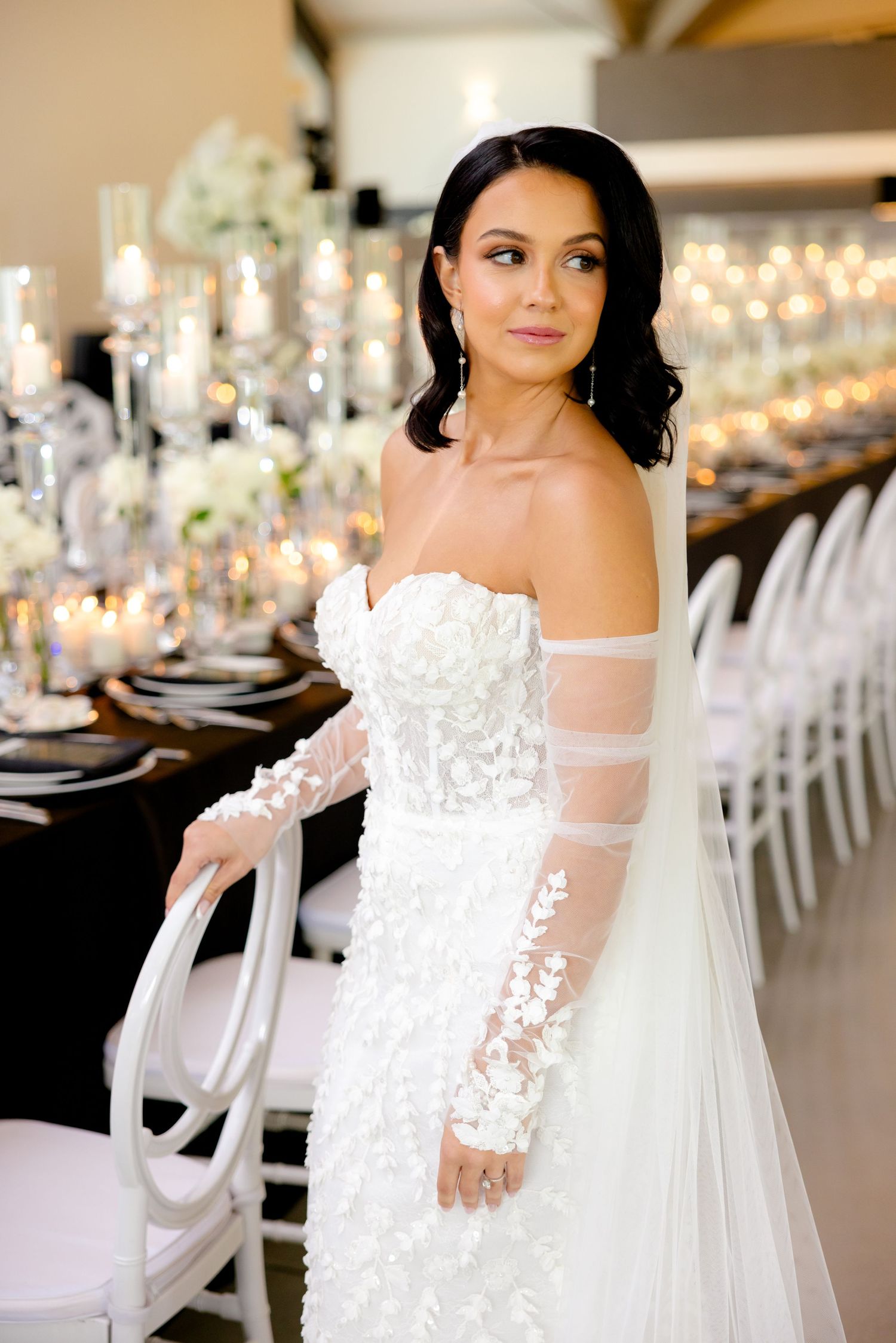 A stunning off-shoulder wedding dress with lace sleeves shown against decorative table settings.