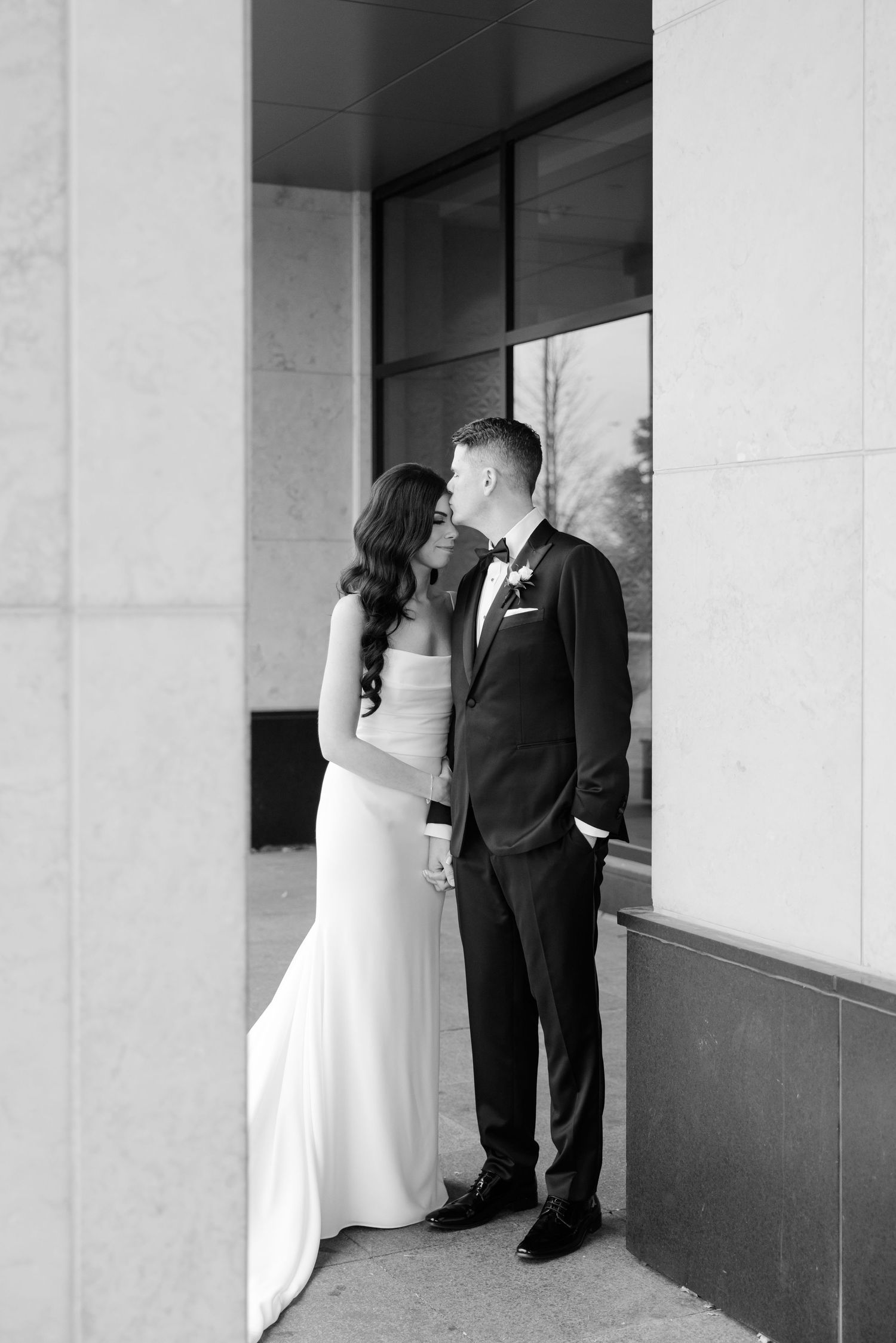 A black and white wedding photo capturing a romantic moment between newlyweds.