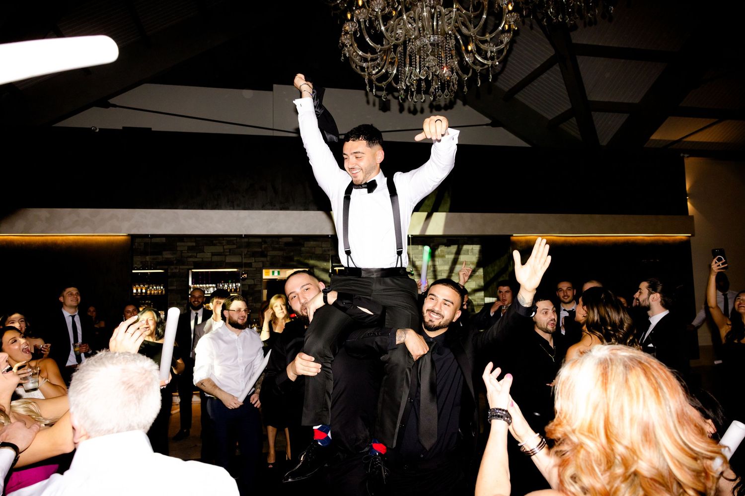 Wedding celebration moment with guest being lifted by crowd during reception party.