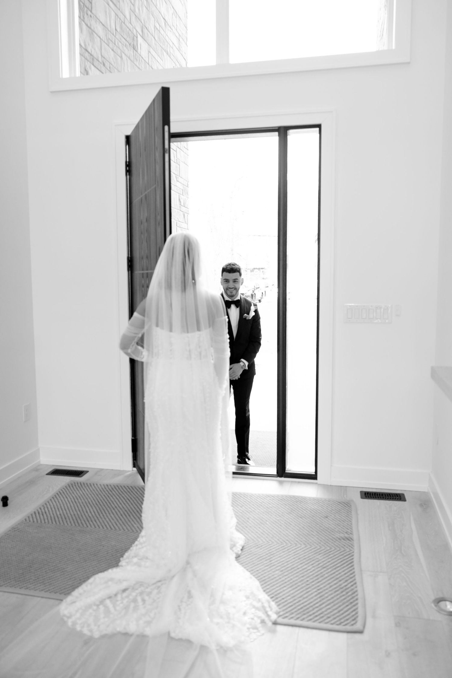 A first look wedding moment captured through a doorway in black and white photography.