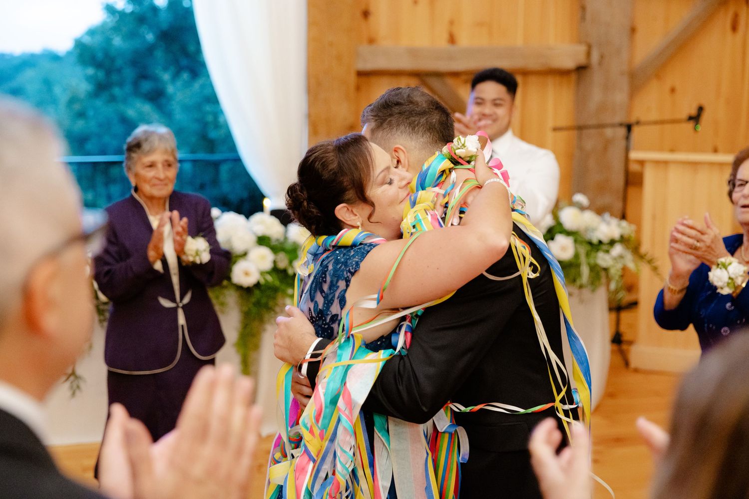 Wedding guests applaud during a special dance moment decorated with colorful ribbons.