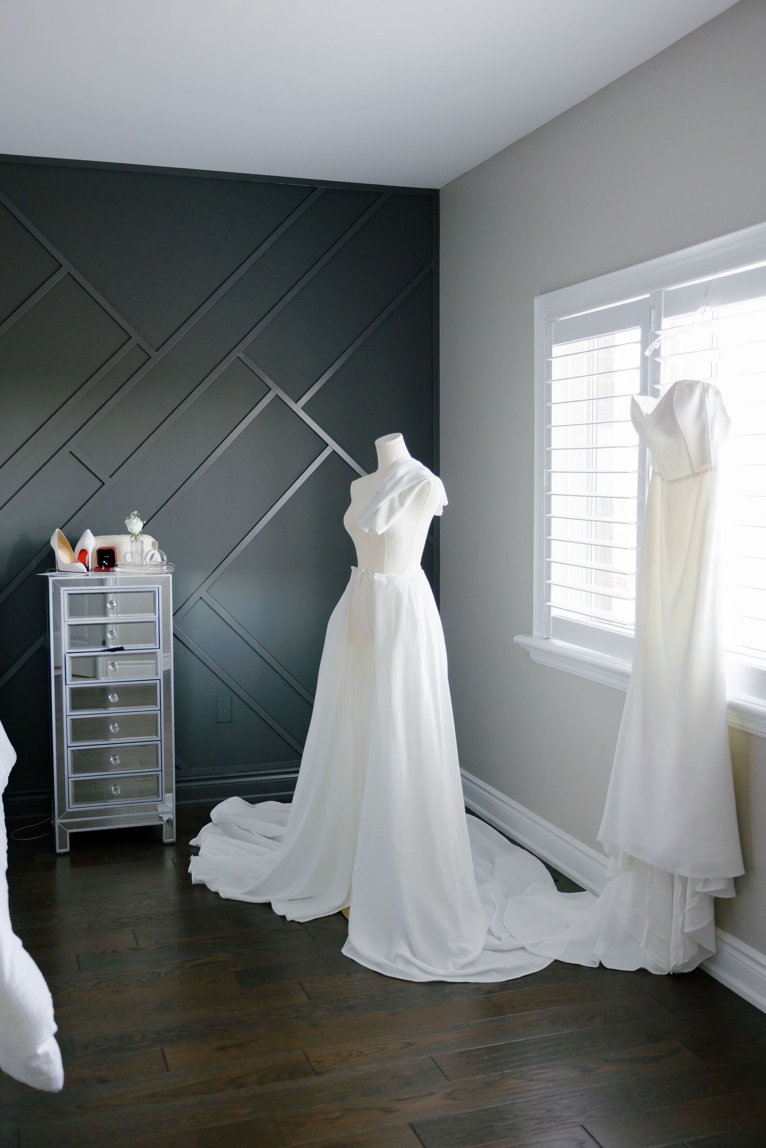 Wedding gowns on display mannequins against a dark accent wall with geometric patterns.