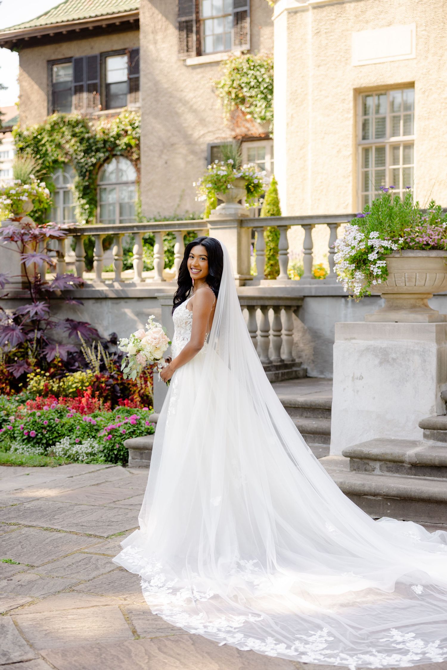 A beautiful bridal portrait in a garden setting with stone balustrades and colorful flowers.