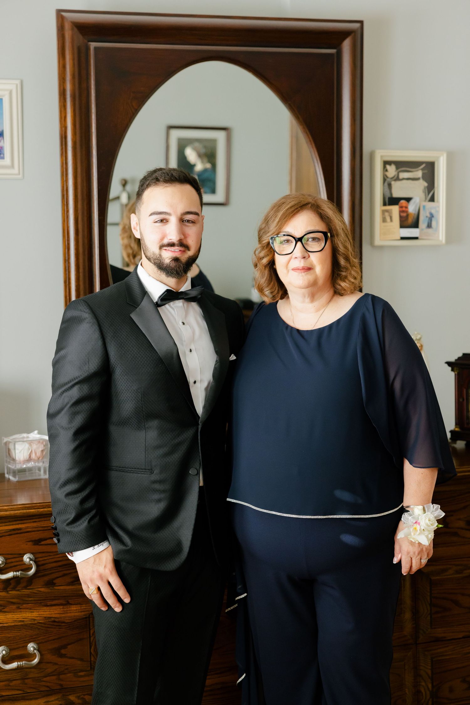 Formal wedding day portrait in front of vintage mirror and wooden dresser.
