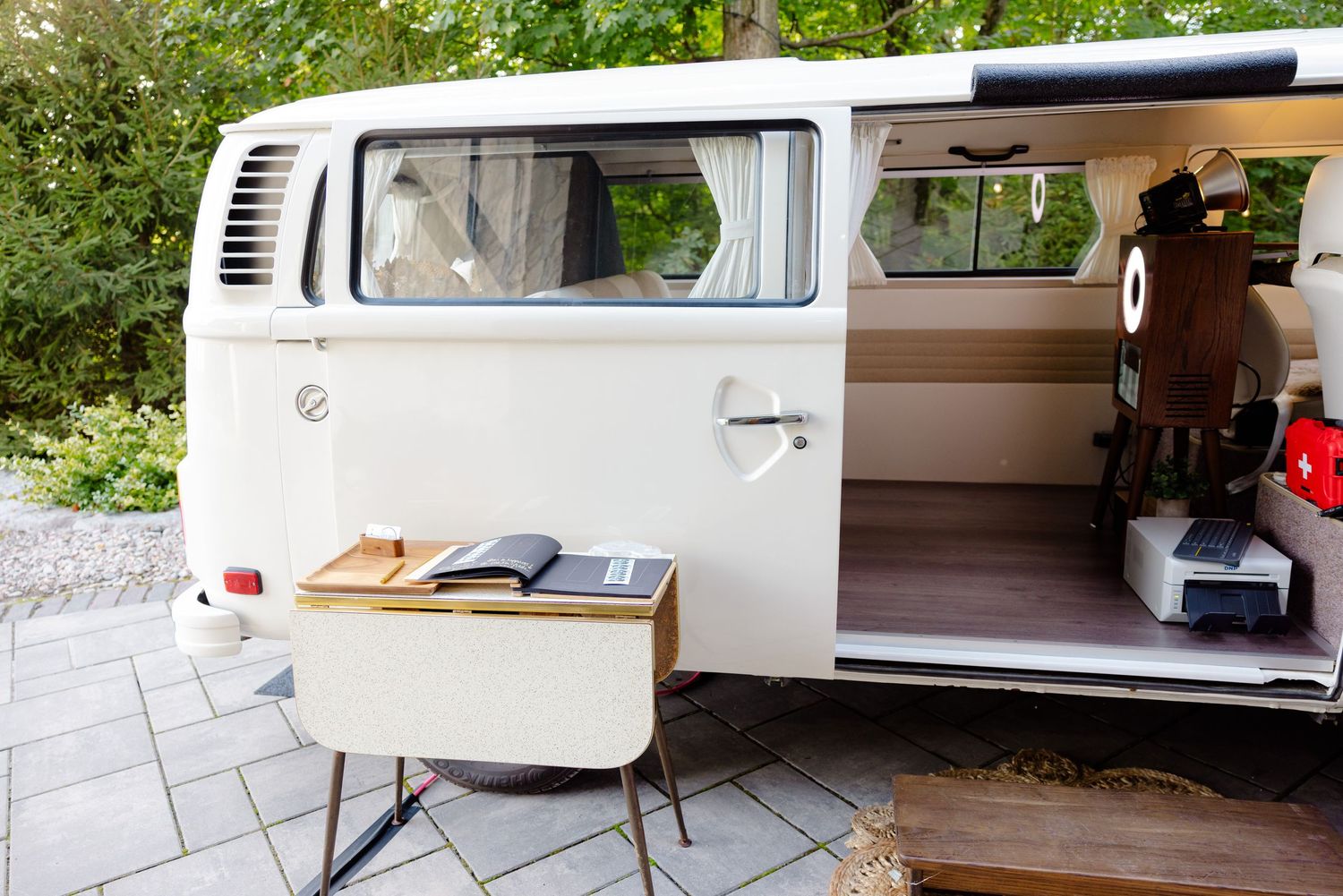 Classic white vintage VW van parked outdoors with door open and wooden box.