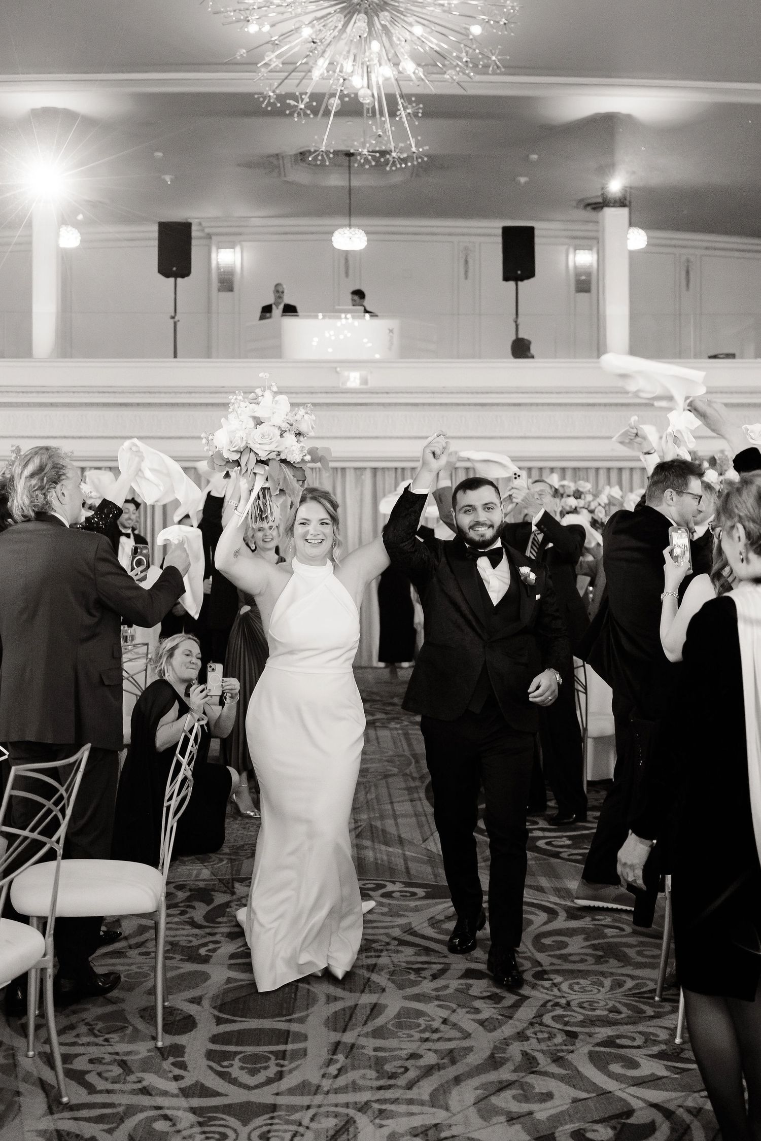 Wedding celebration with guests dancing and cheering in an elegant ballroom.