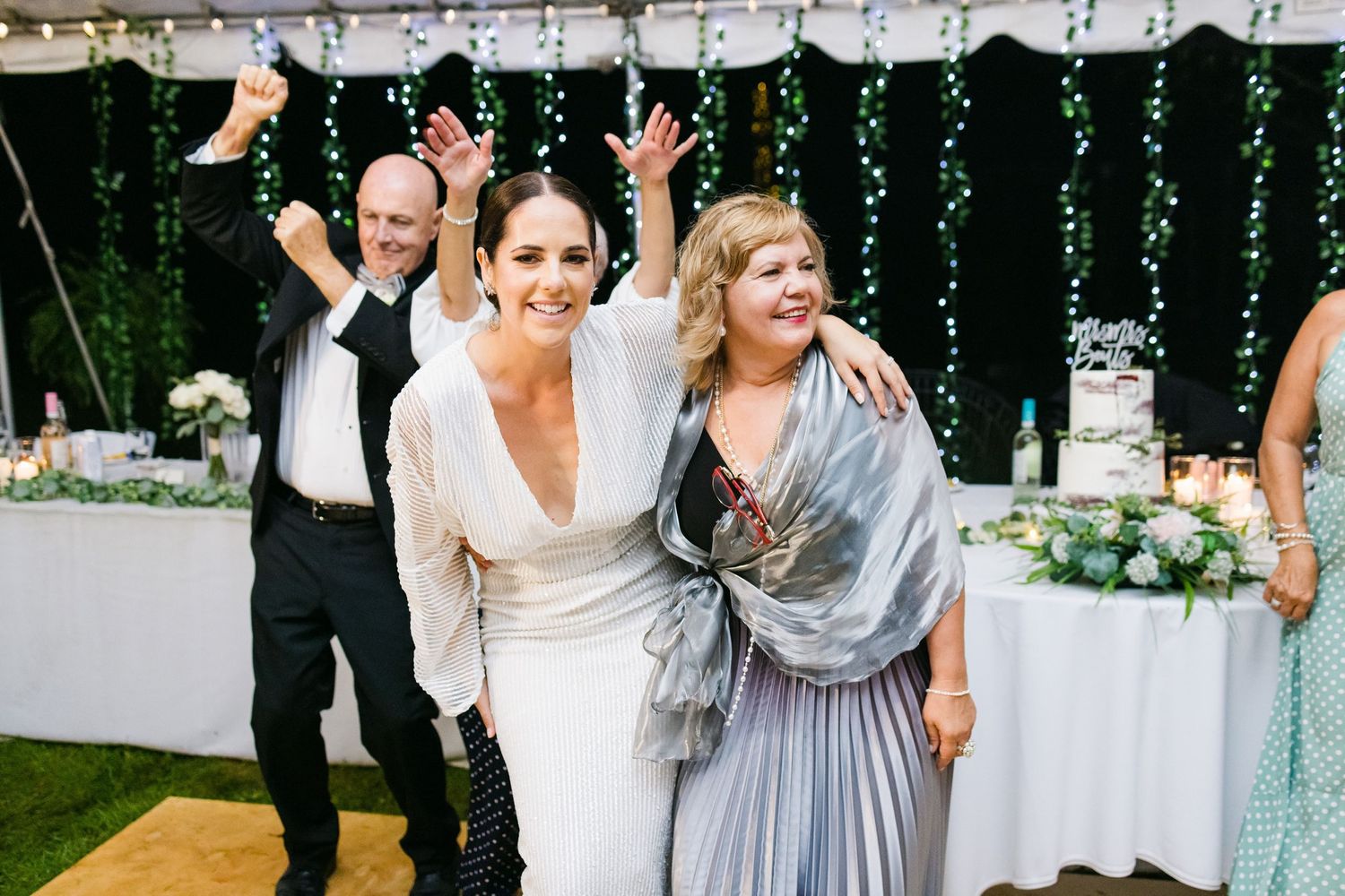 Wedding guests celebrating and dancing enthusiastically at an outdoor reception.