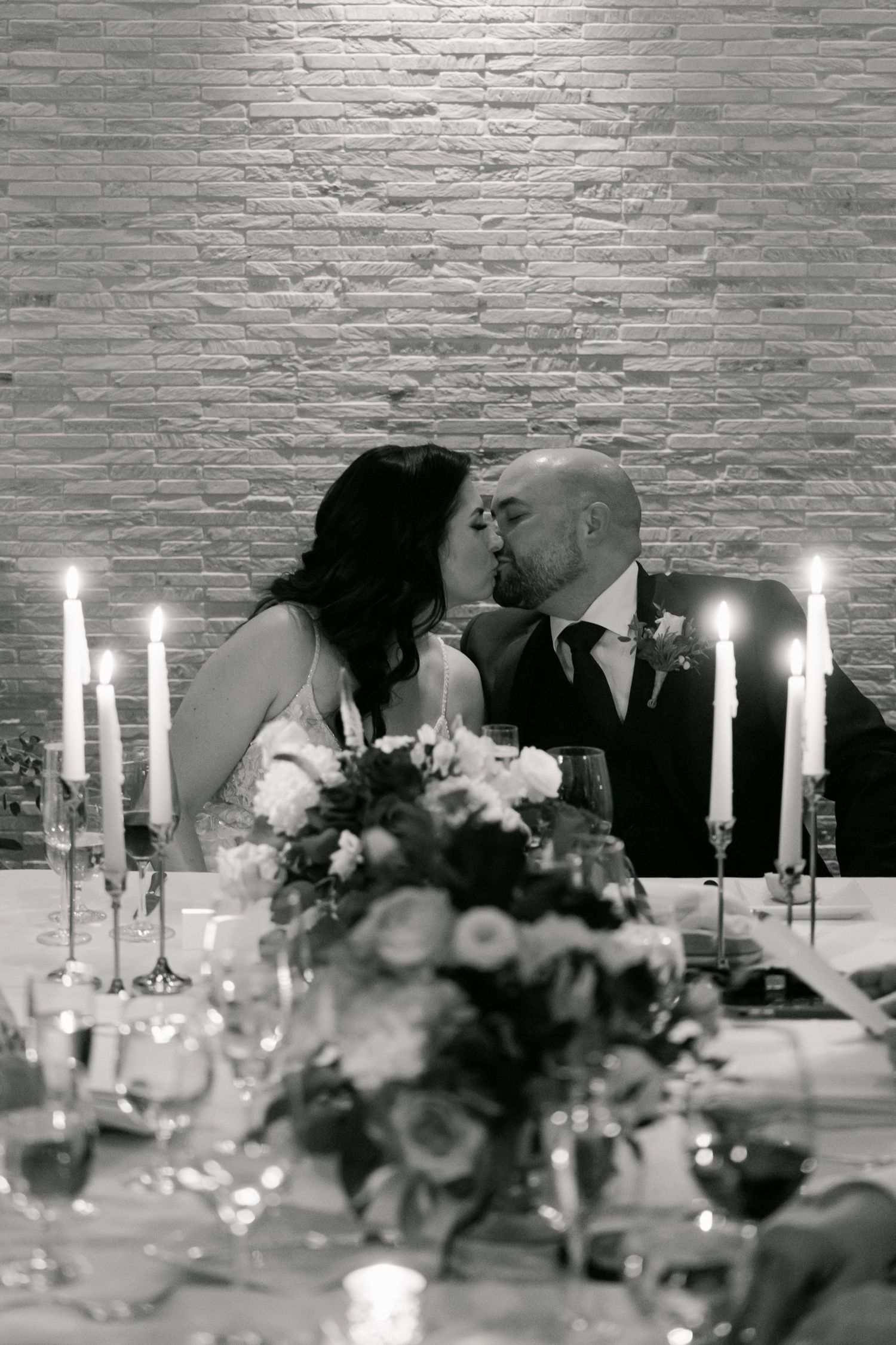 Black and white romantic table setting with candles and floral centerpiece.