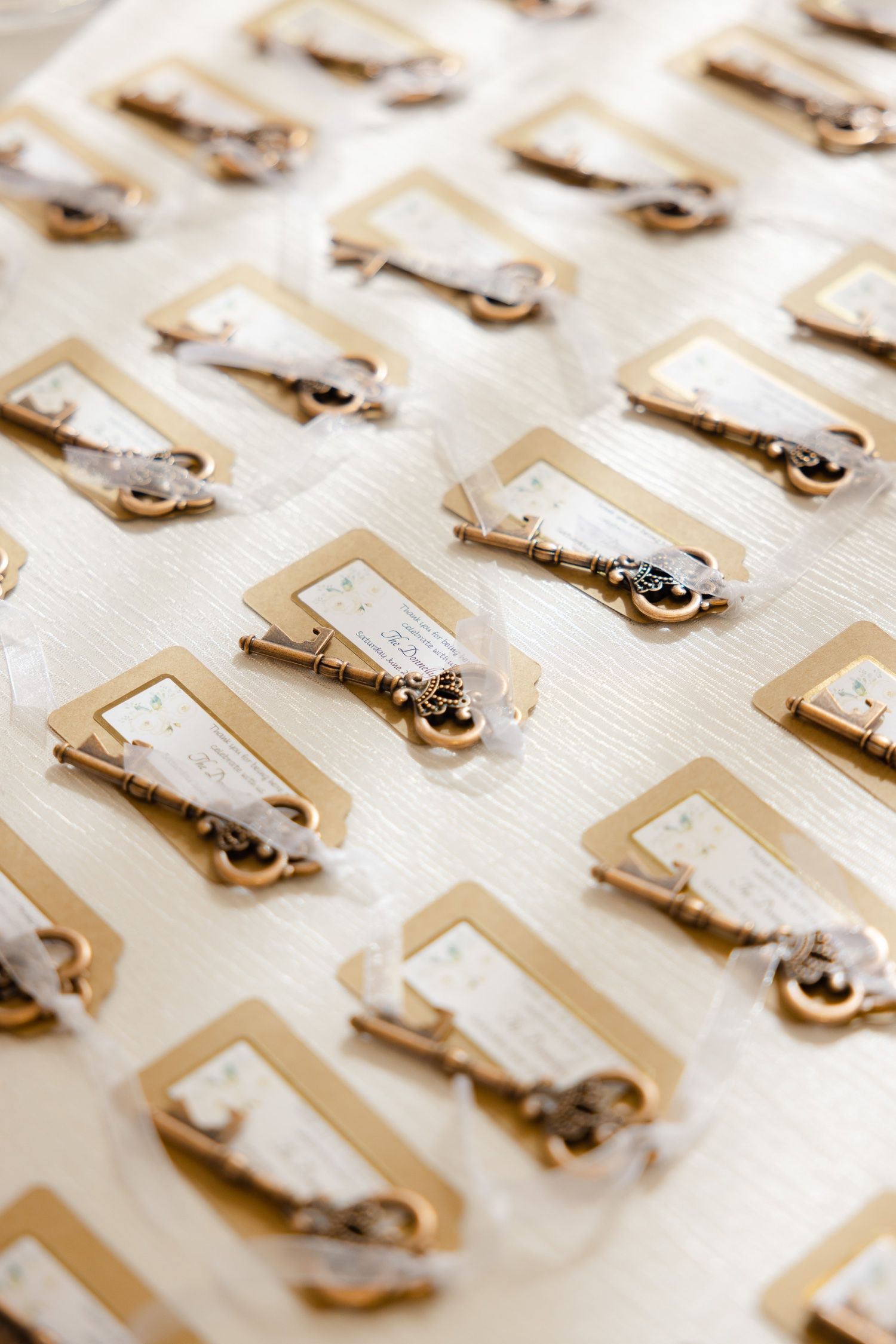 Organized arrangement of wedding place cards with vintage keys on cream-colored background.
