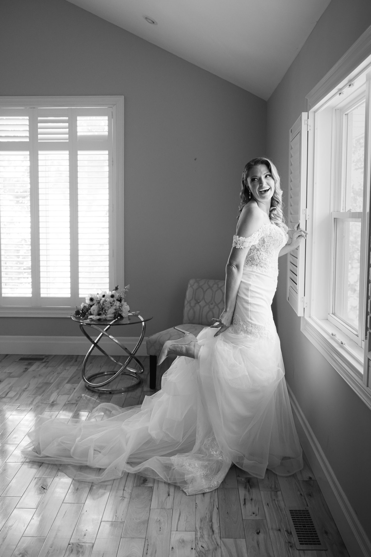 A bride poses by a window in a fitted mermaid wedding gown in black and white.