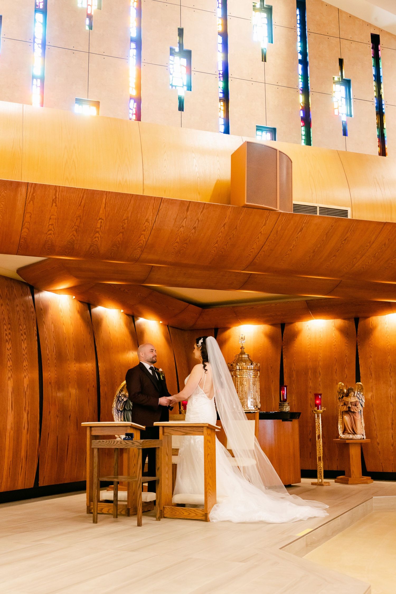 Wedding ceremony under modern hanging light fixtures in contemporary church sanctuary.