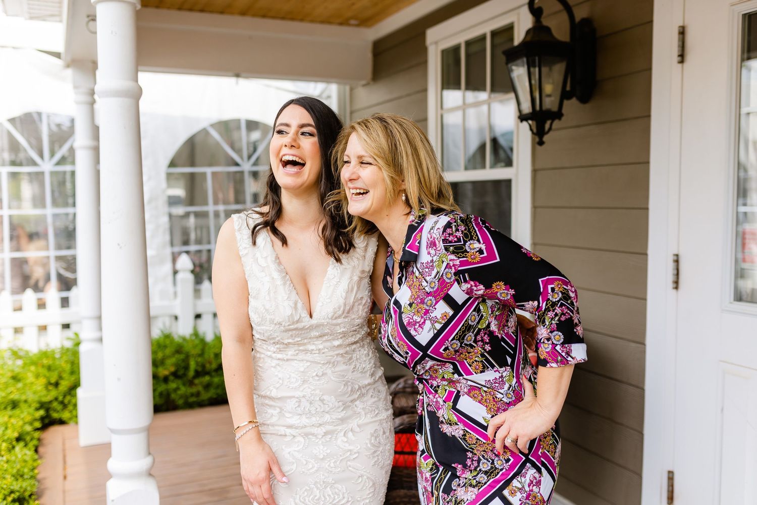 Two people sharing laughter on a covered porch with white columns.