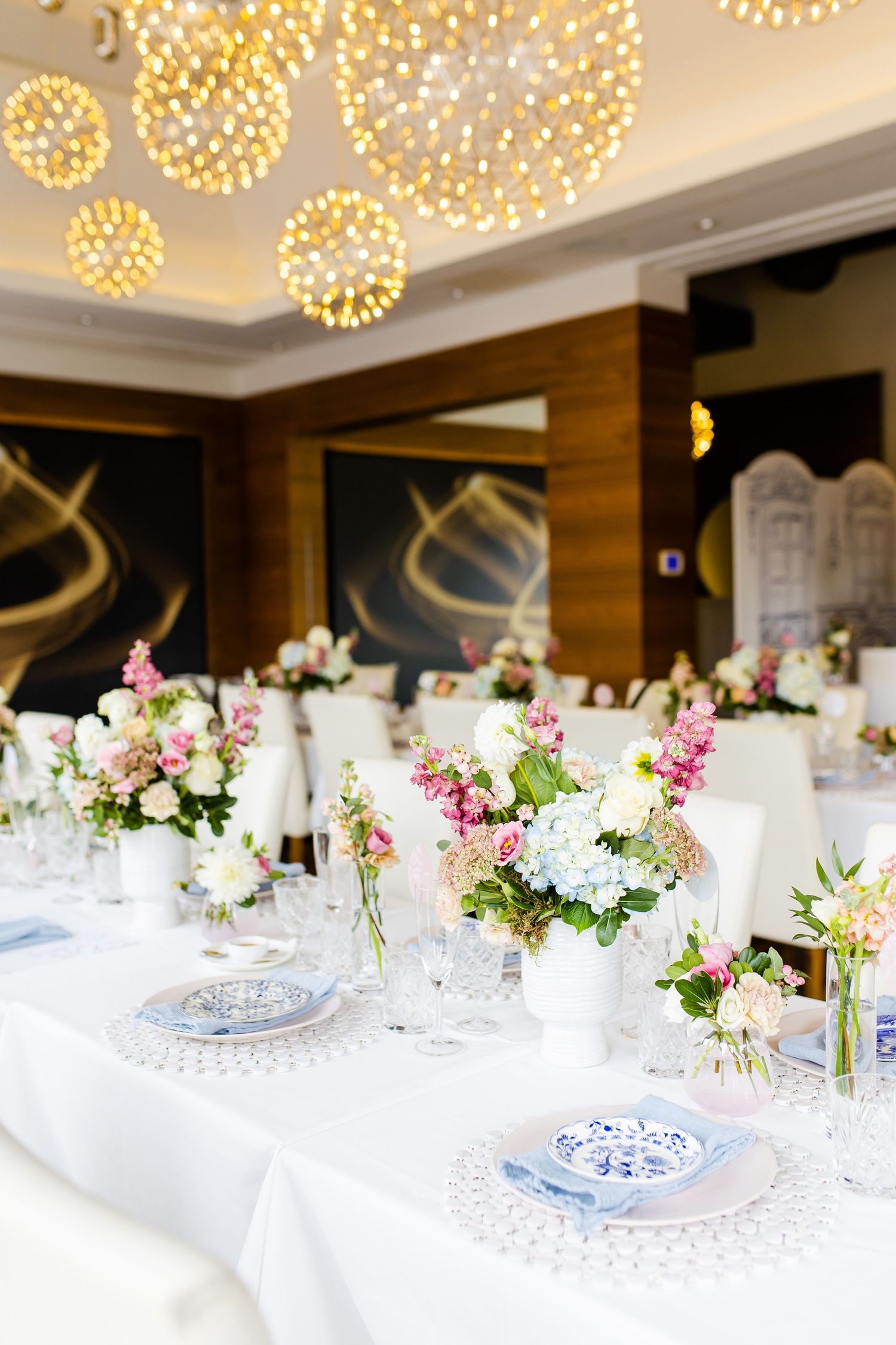 Luxurious dining setup with dandelion-shaped ceiling lights and elegant table settings.