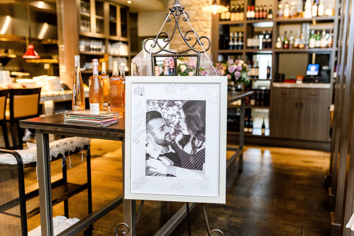 Restaurant interior with framed photo display and wine bottles on shelves.