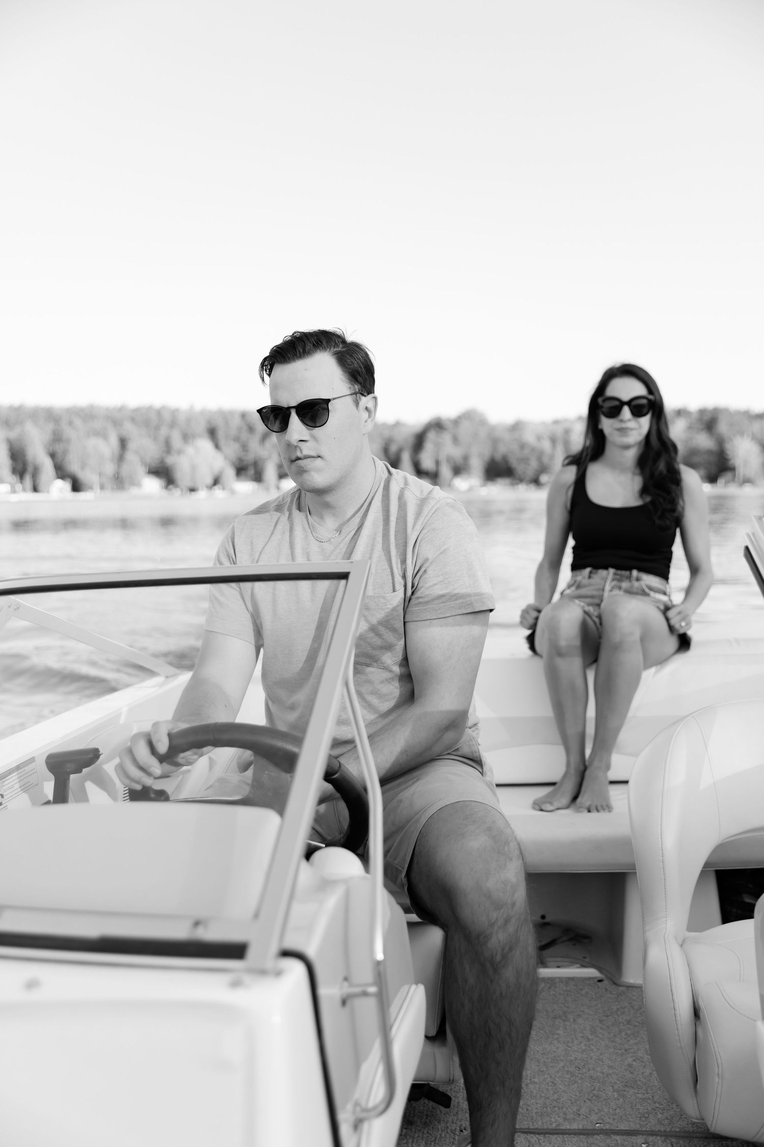 Black and white photo of couple on boat with driver at helm and passenger relaxing.