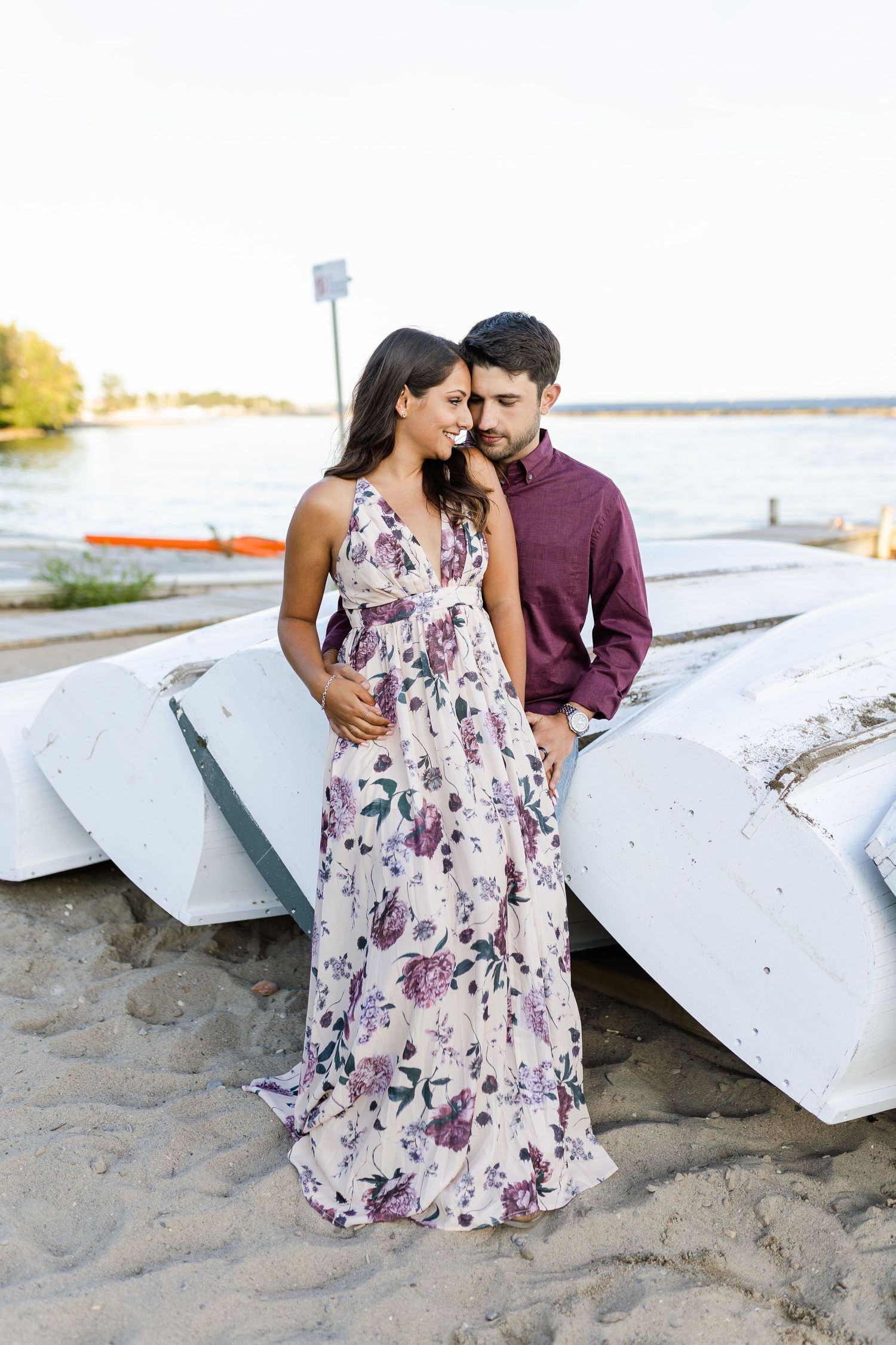 A romantic moment shared between a couple next to white canoes on the beach.